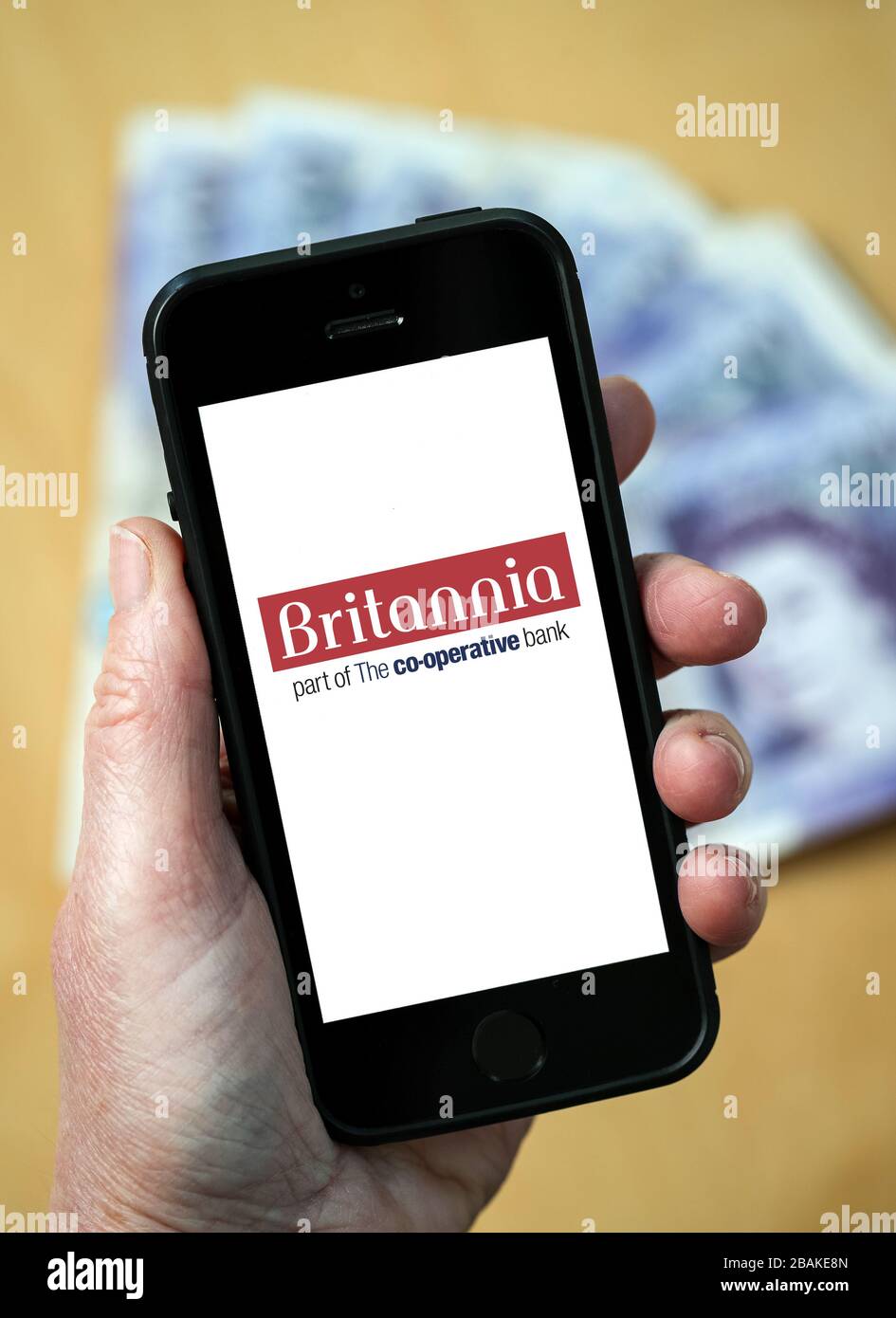 A woman holding a mobile phone showing Britannia Building Society (editorial use only) Stock Photo