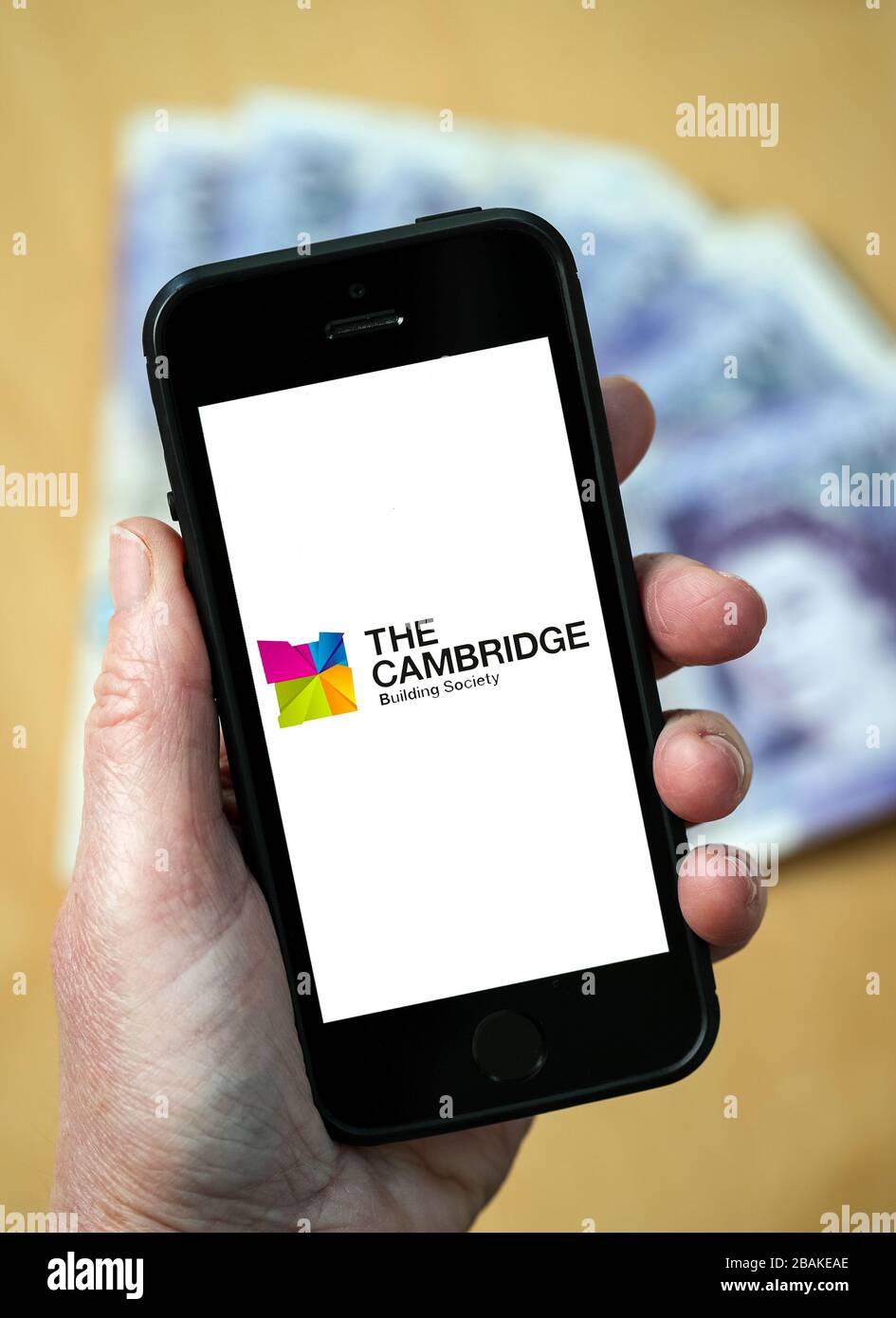A woman holding a mobile phone showing The Cambridge Building Society (editorial use only) Stock Photo