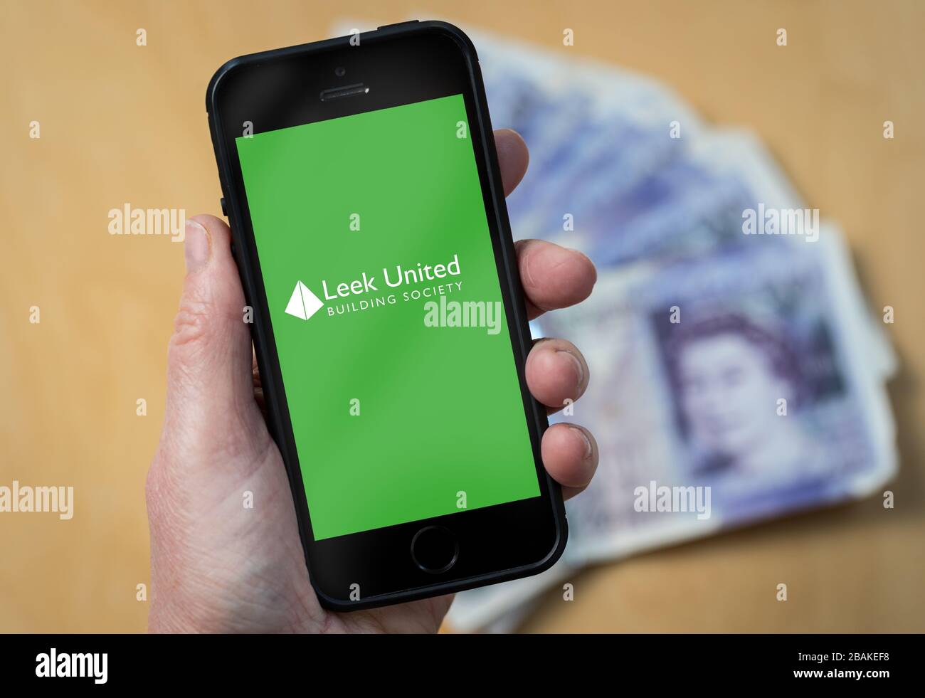 A woman holding a mobile phone showing Leek United Building Society (editorial use only) Stock Photo