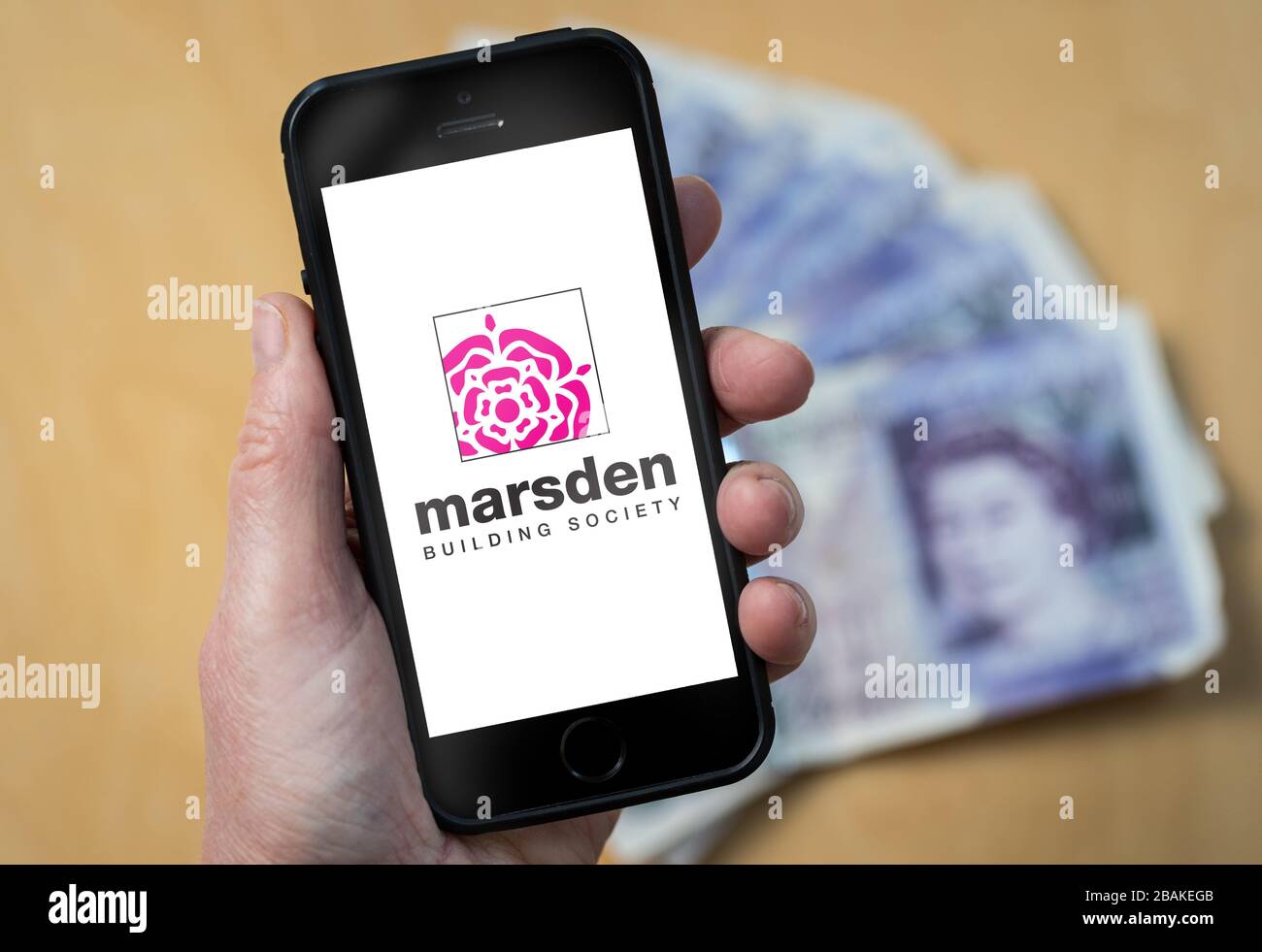 A woman holding a mobile phone showing Marsden Building Society (editorial use only) Stock Photo