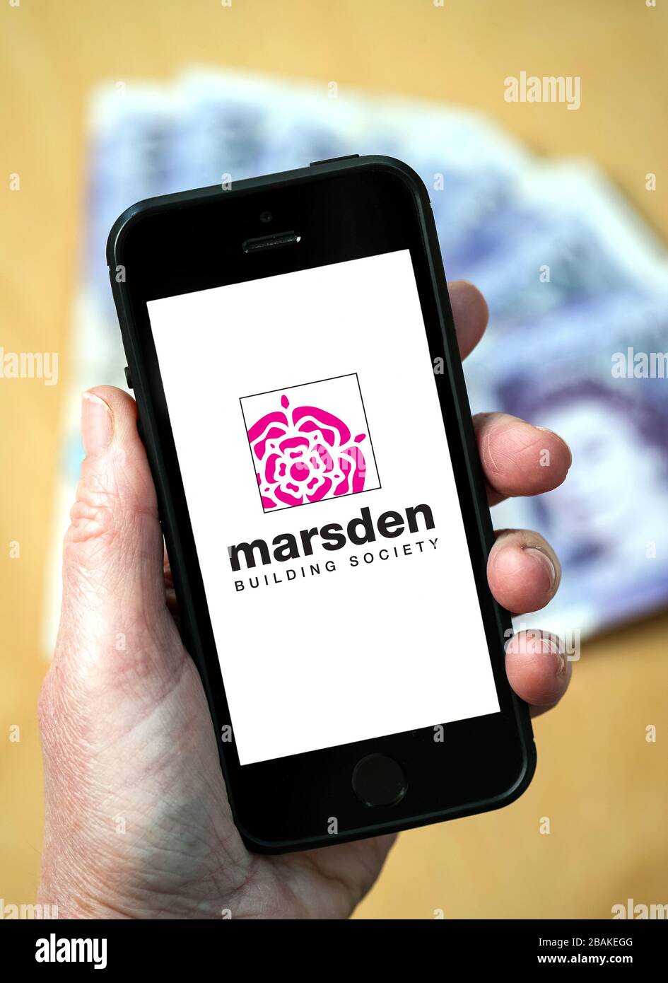 A woman holding a mobile phone showing Marsden Building Society (editorial use only) Stock Photo