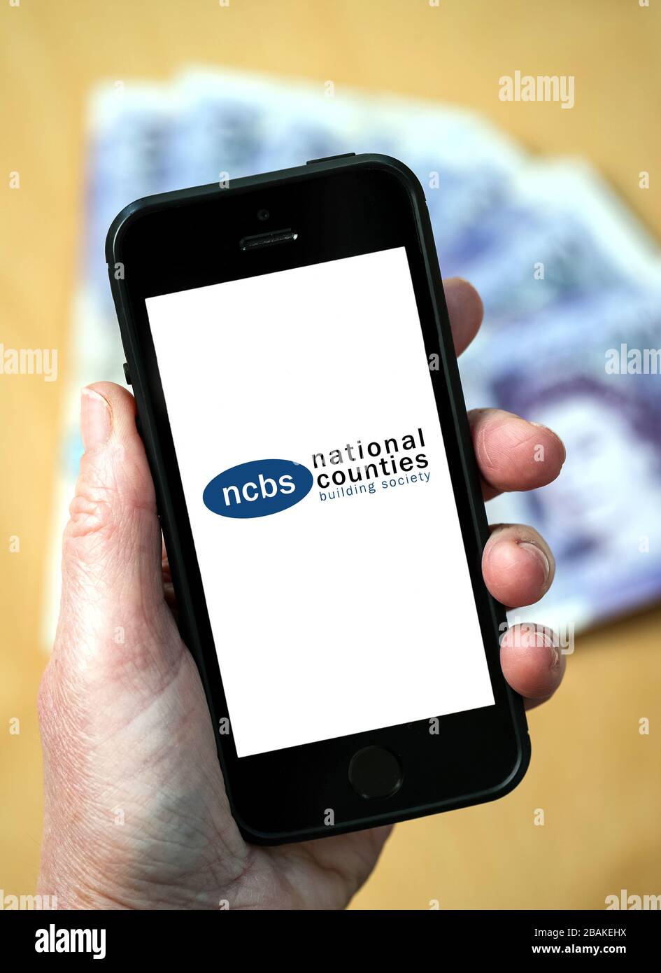 A woman holding a mobile phone showing National Counties Building Society (editorial use only) Stock Photo