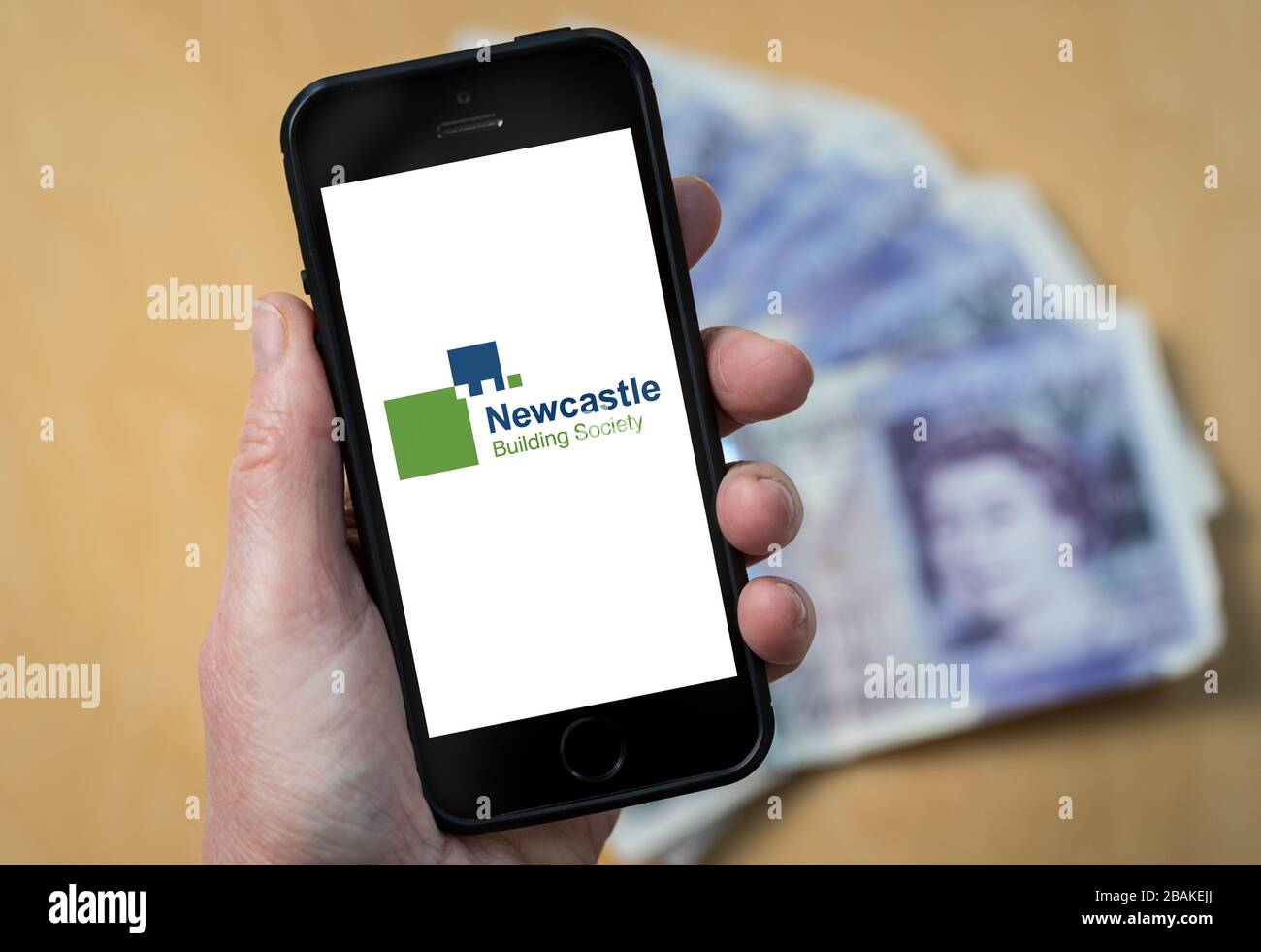 A woman holding a mobile phone showing Newcastle Building Society (editorial use only) Stock Photo