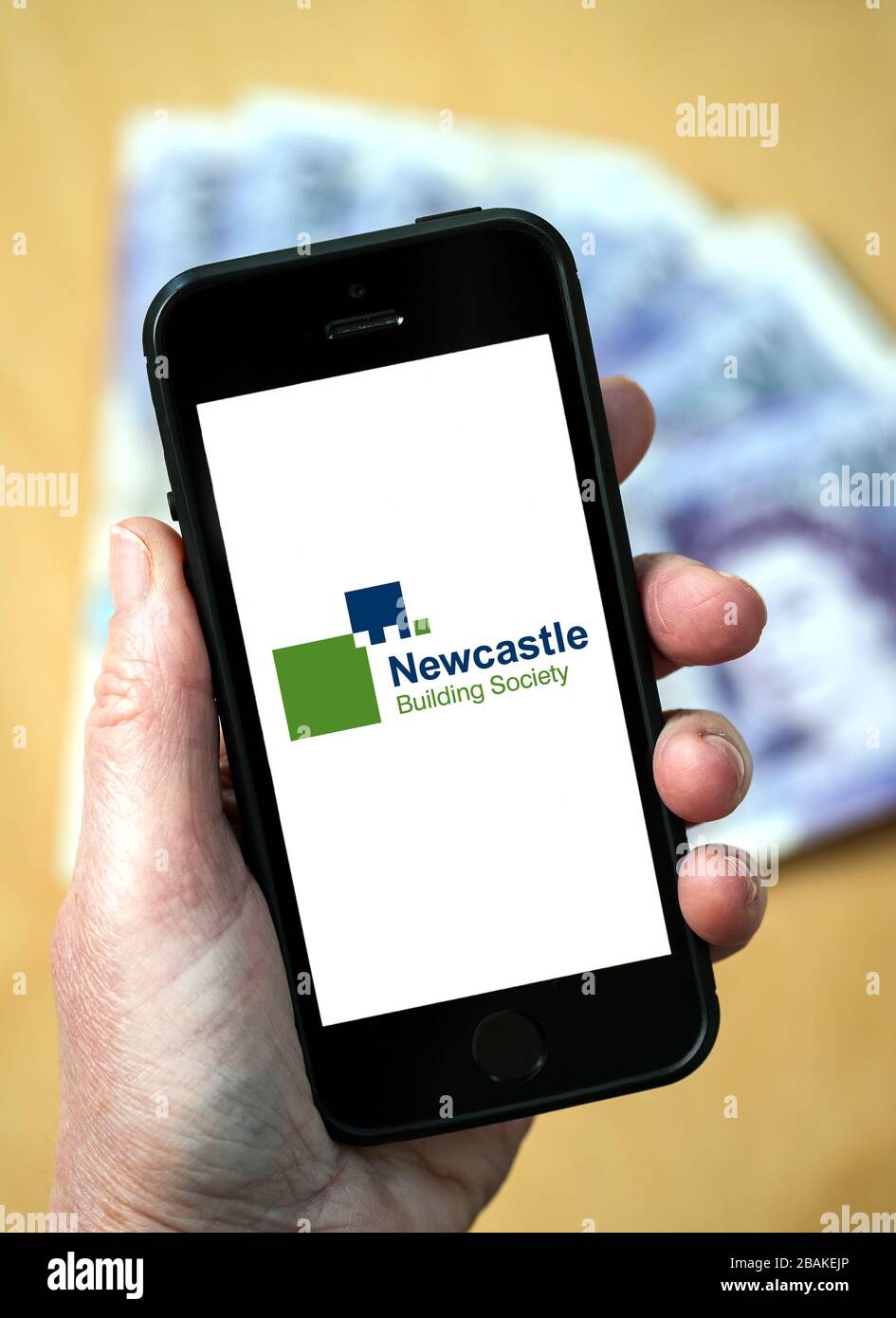 A woman holding a mobile phone showing Newcastle Building Society (editorial use only) Stock Photo
