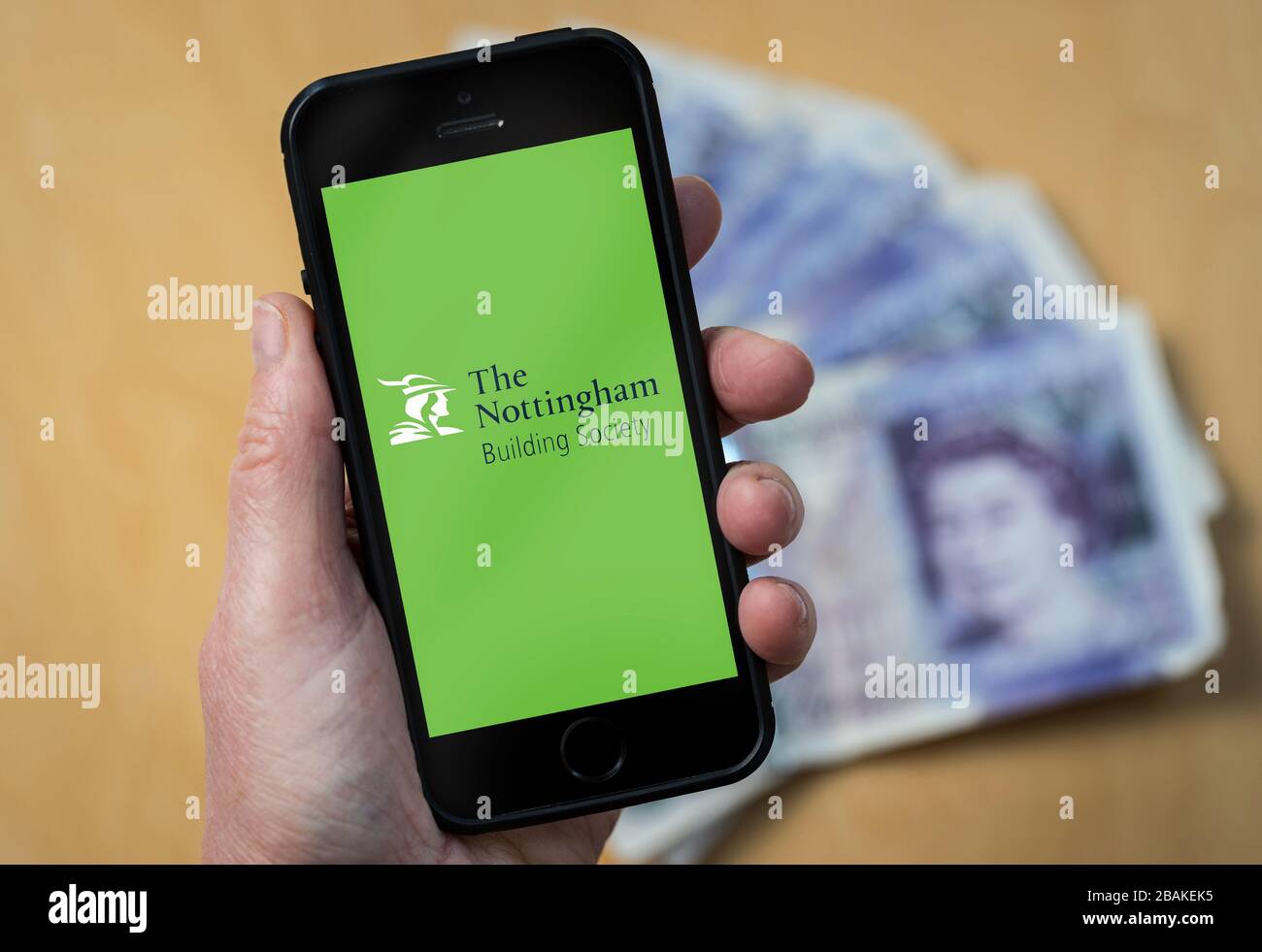 A woman holding a mobile phone showing Nottingham Building Society (editorial use only) Stock Photo