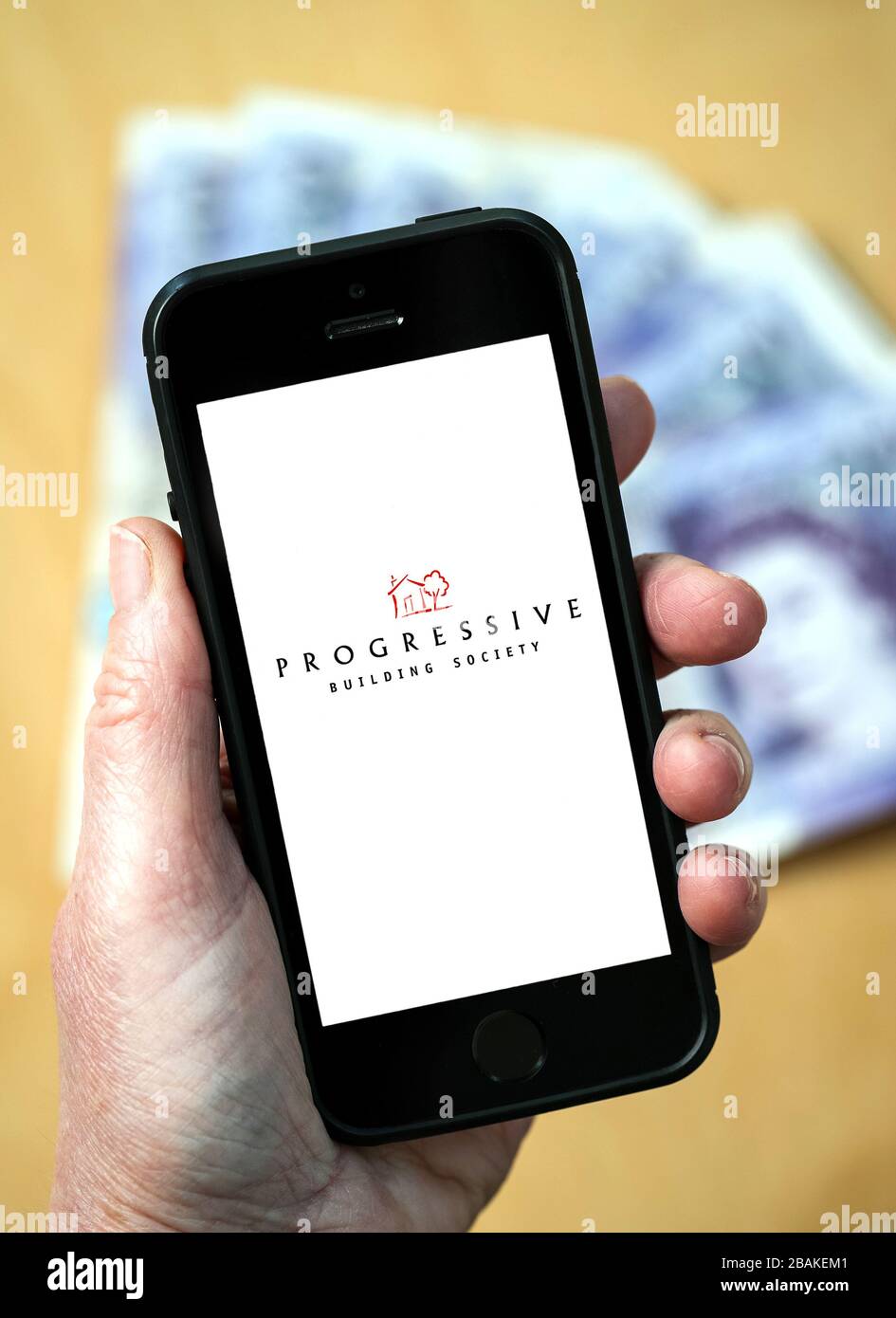 A woman holding a mobile phone showing Progressive Building Society (editorial use only) Stock Photo