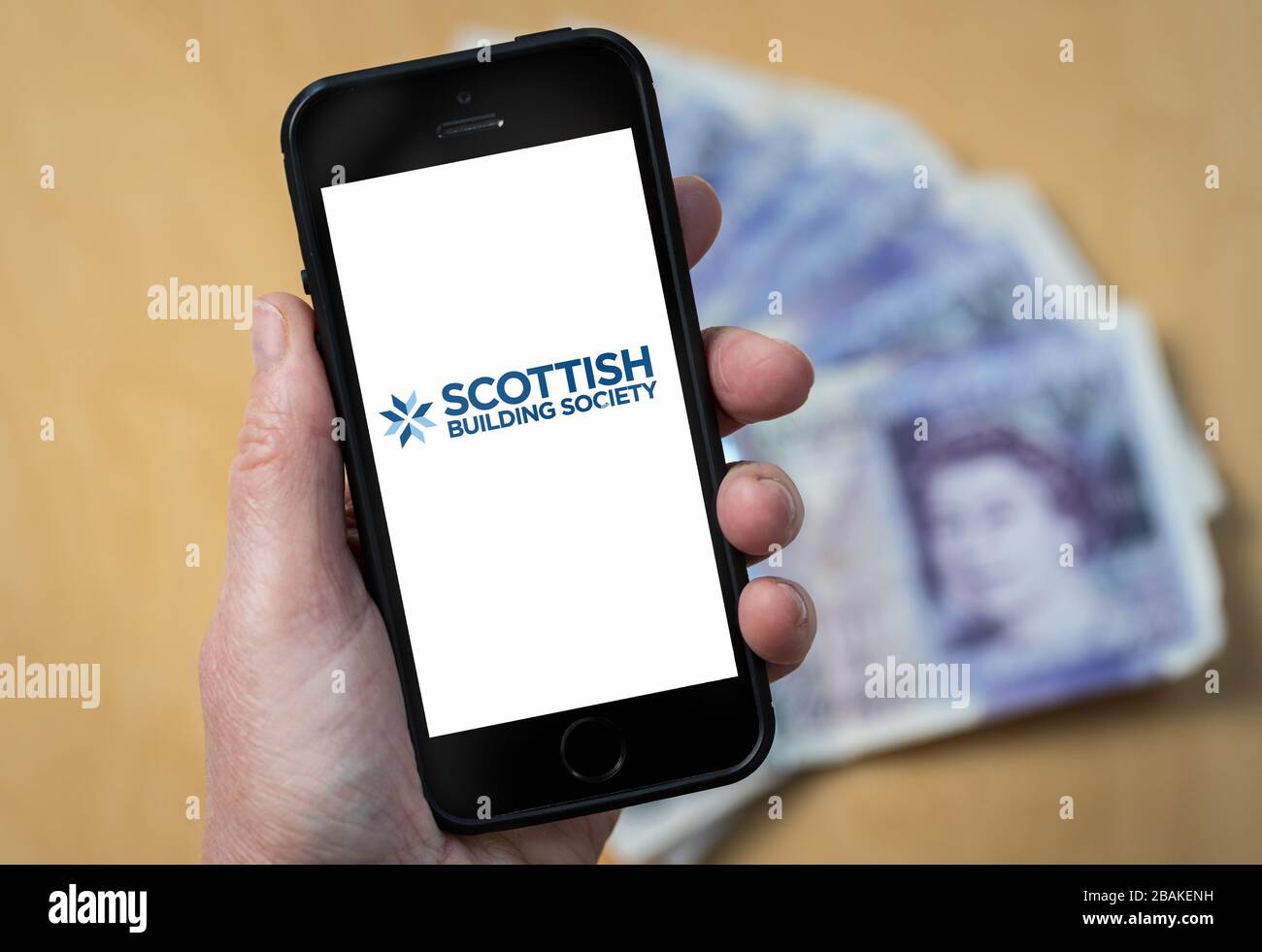 A woman holding a mobile phone showing Scottish Building Society (editorial use only) Stock Photo