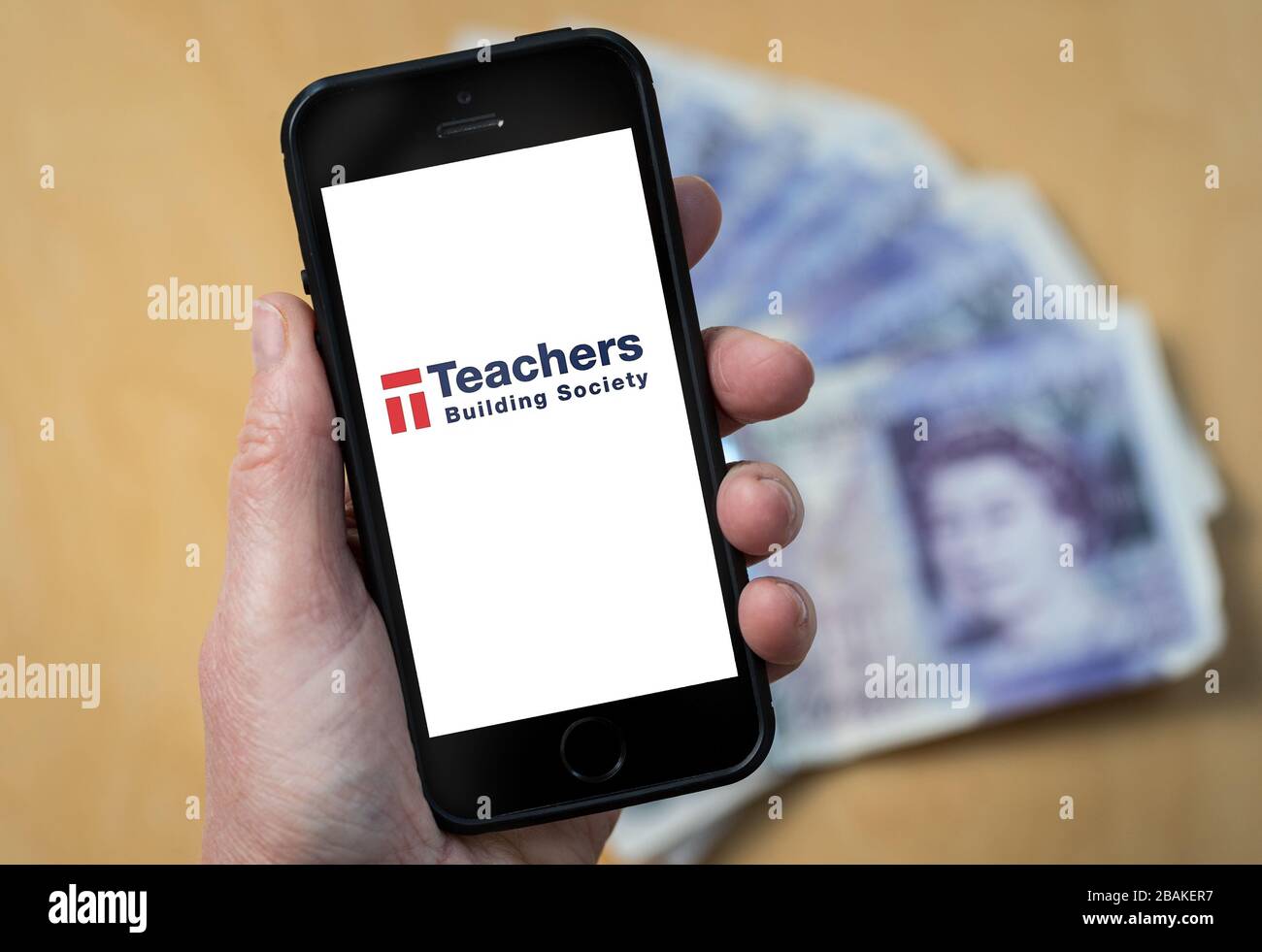 A woman holding a mobile phone showing Teachers Building Society (editorial use only) Stock Photo