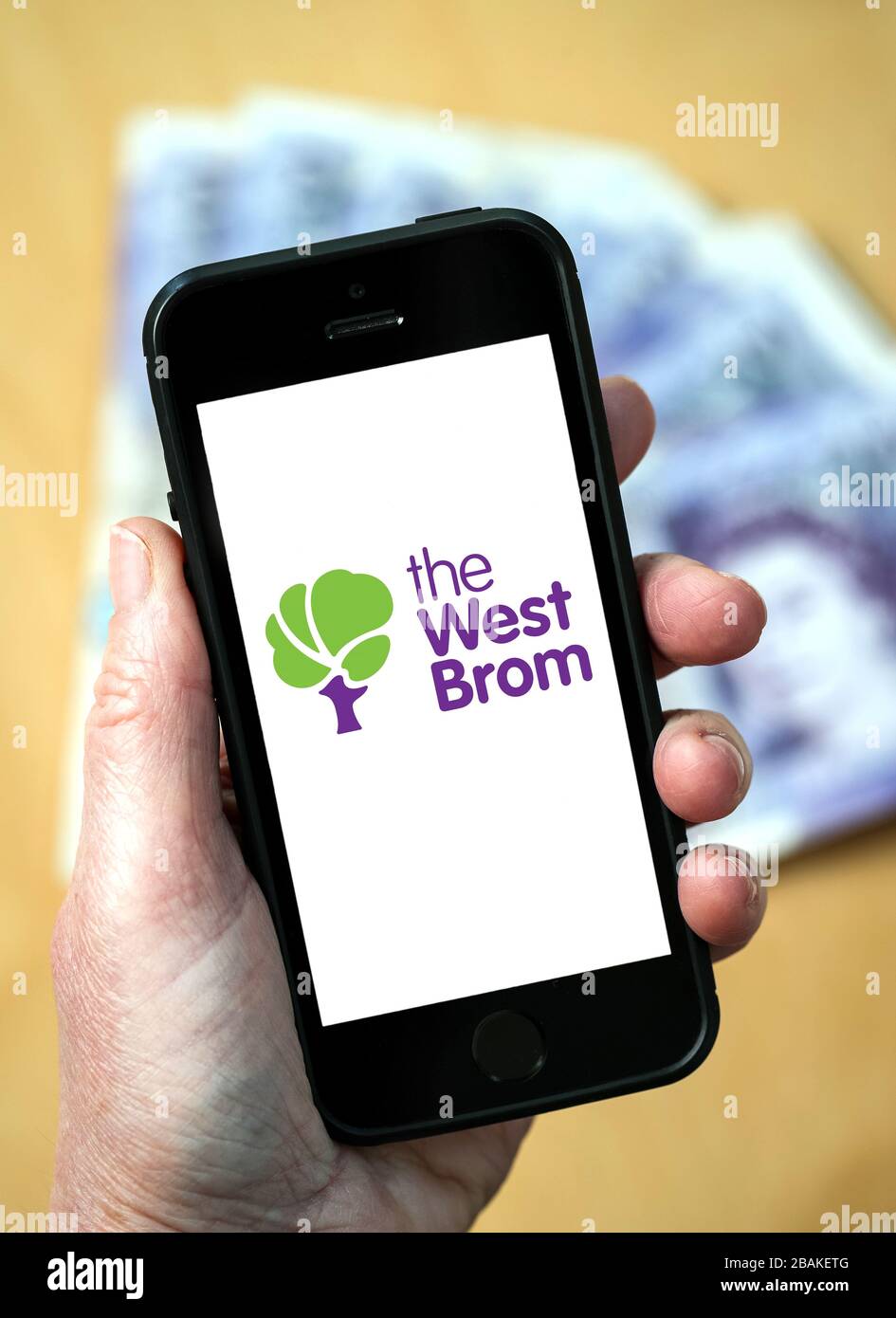 A woman holding a mobile phone showing The West Brom Building Society (editorial use only) Stock Photo