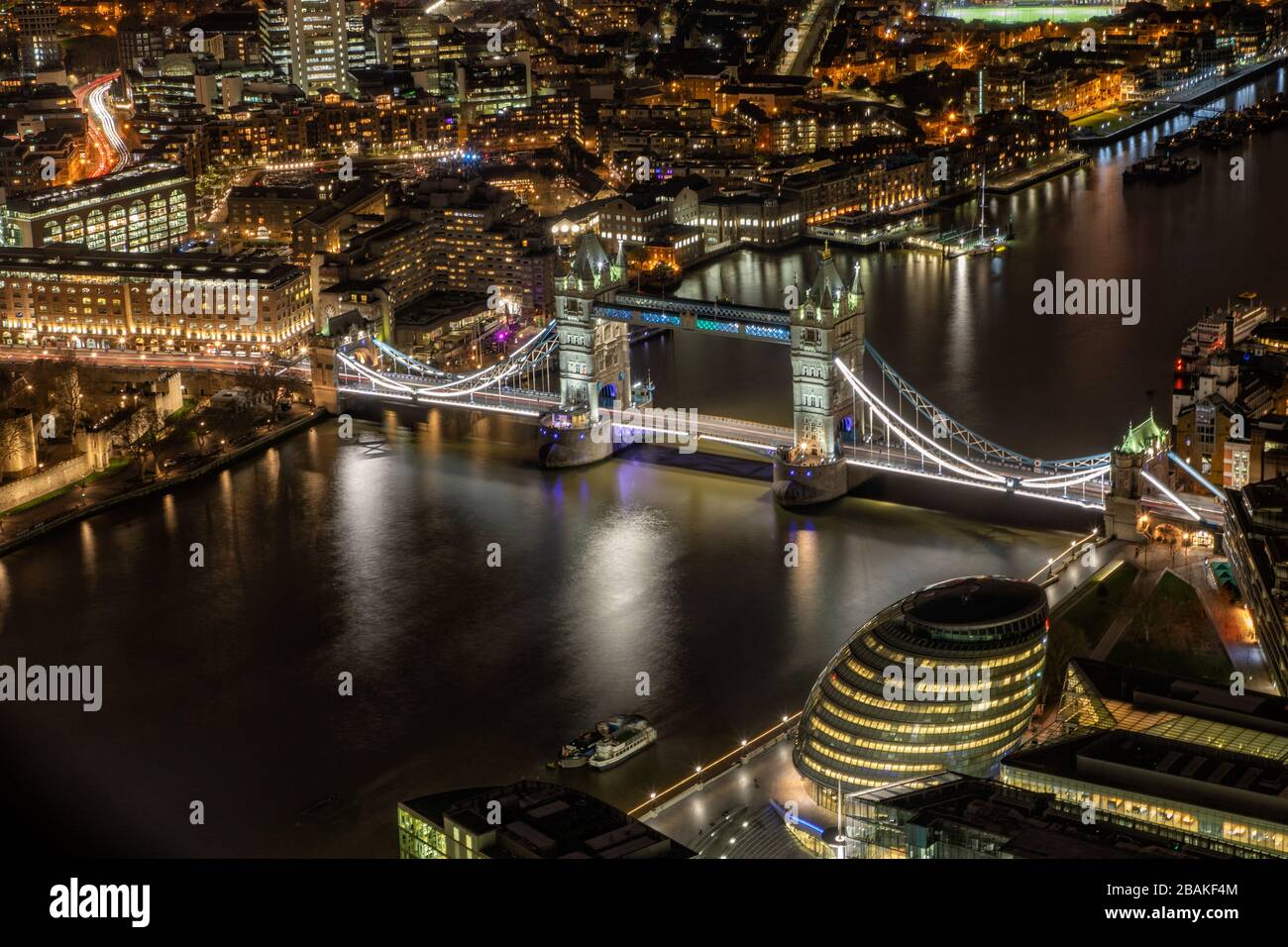 Tower Bridge over the River Thames at night with illuminated office buildings, the tower of London and leading towards Canary Wharf Stock Photo