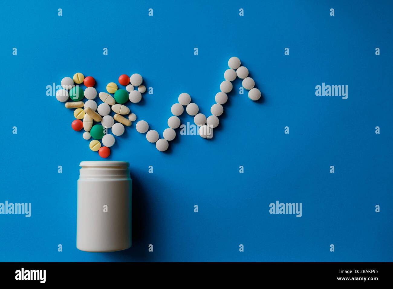 Heap of pills on blue background Assorted pharmaceutical medicine pills, tablets and capsules and bottle on blue background. Stock Photo