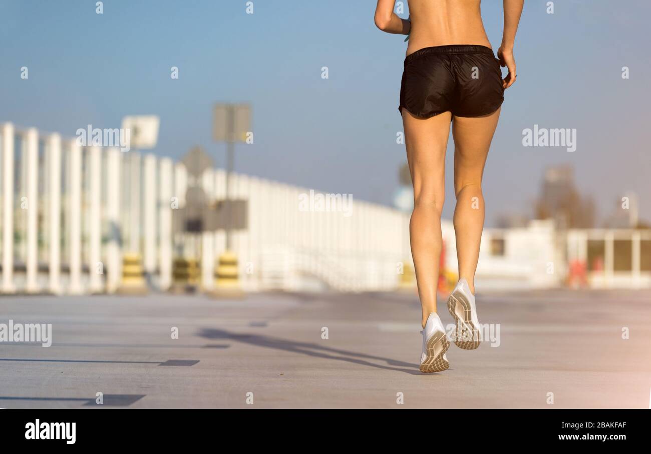 Young woman doing fitness exercise on parking level in the city at sunset Stock Photo