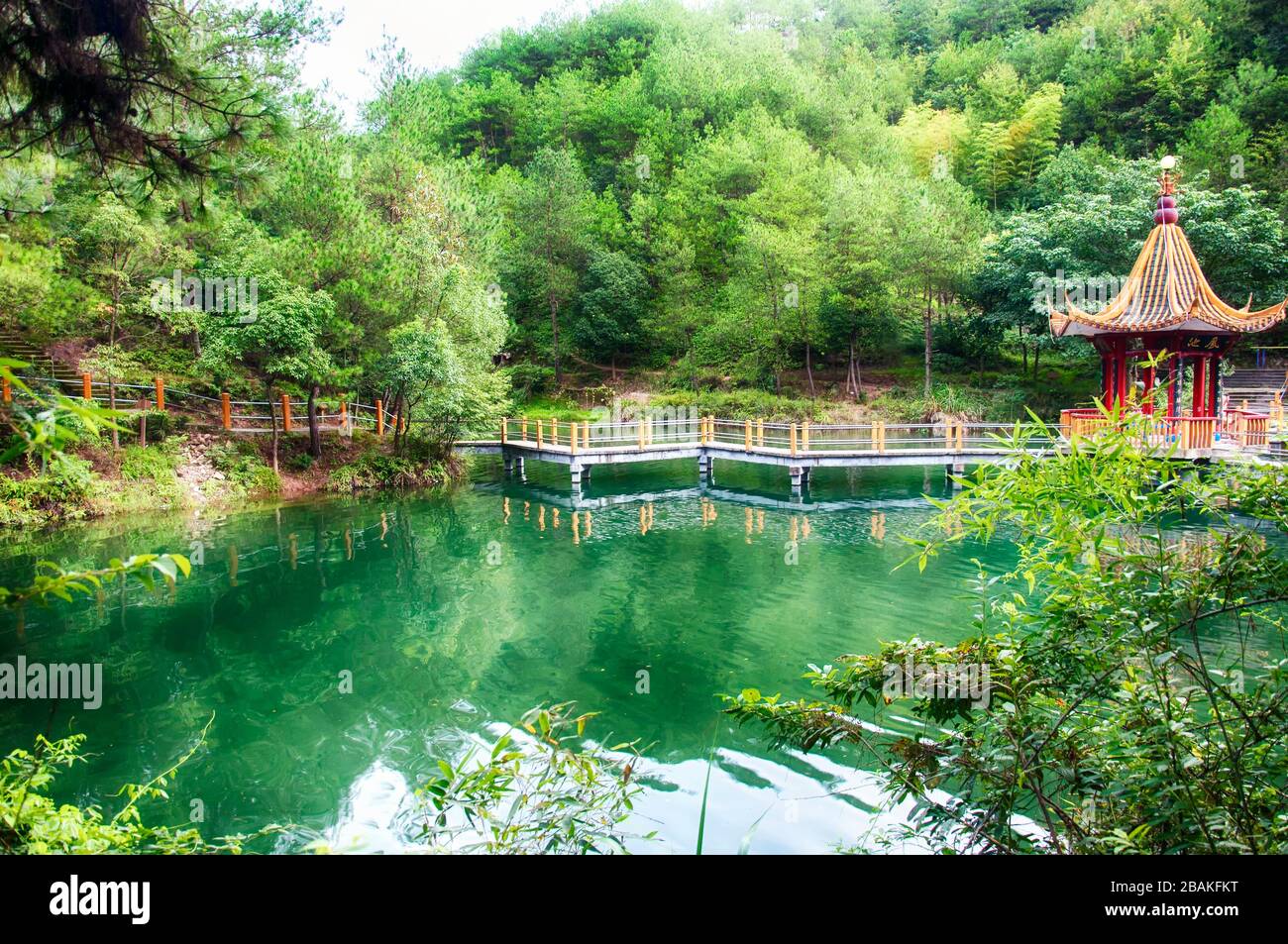 A green lake and chinese gazebo at the feng huang shan gong yuan or phoenix mountain park in Lishui China on an overcast day in Zhejiang province. Stock Photo