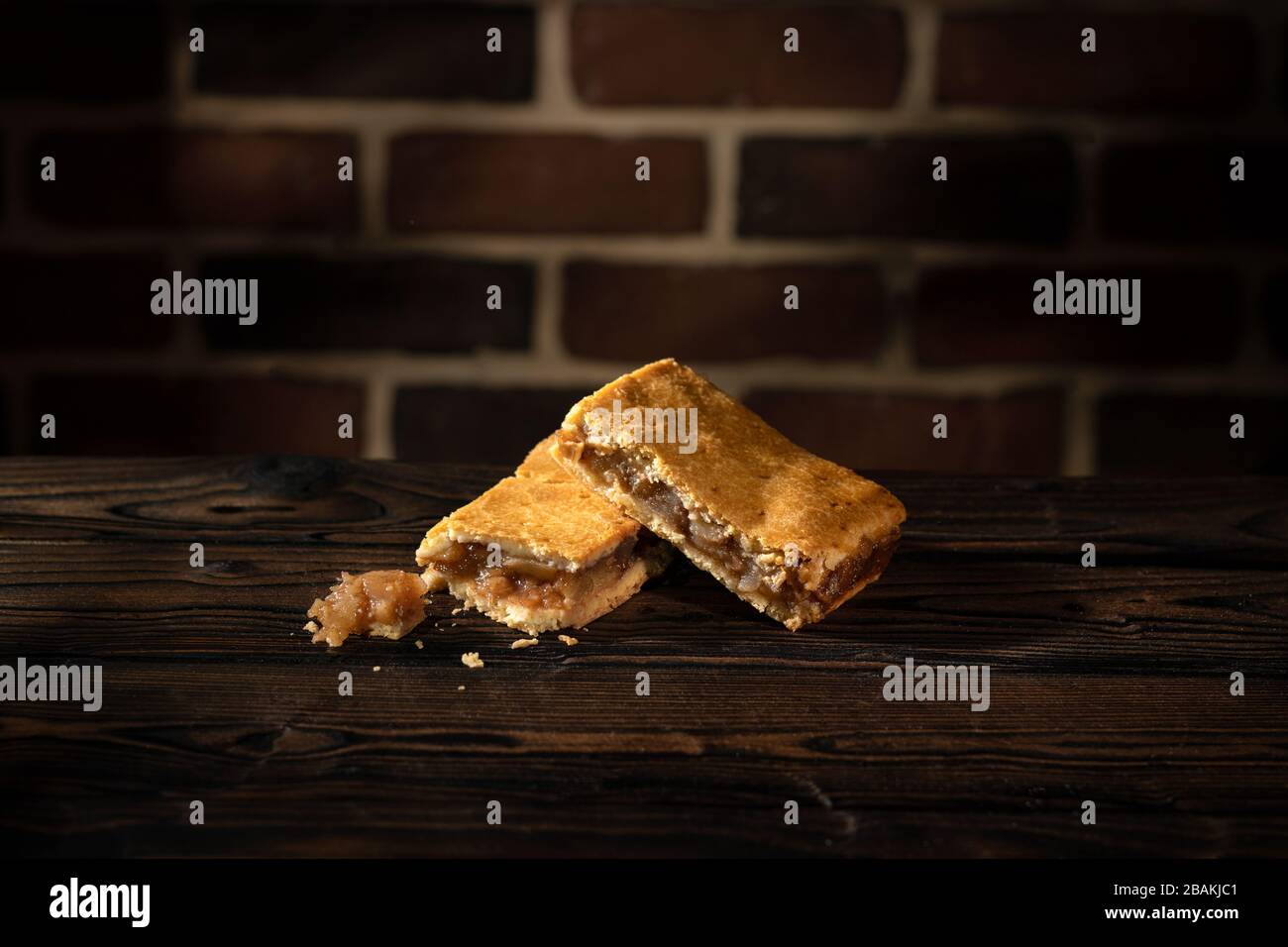 Two apple cake on wooden table and brick wall background Stock Photo