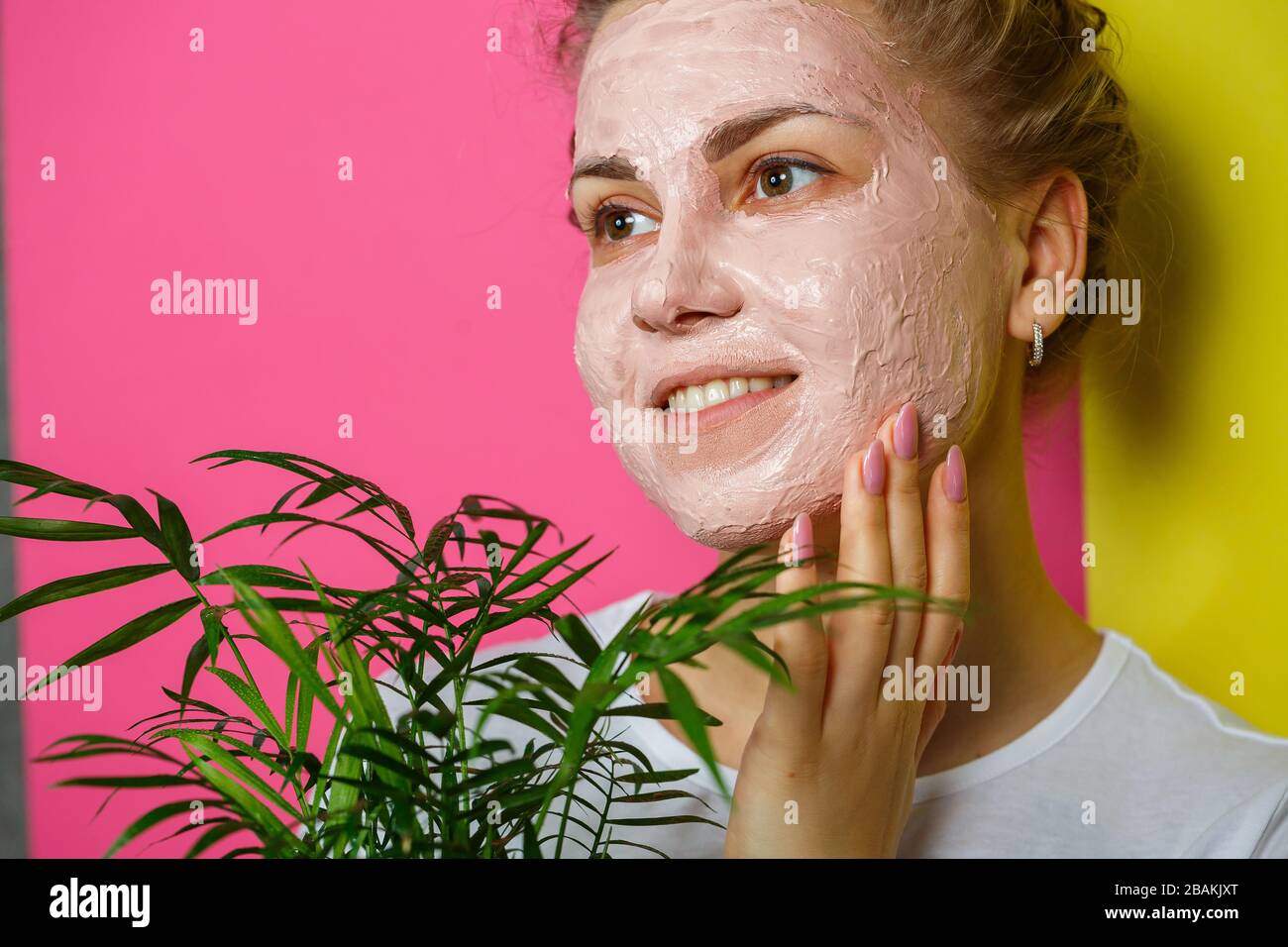 Beautiful young girl with a refreshing mask on her face. Holding a decorative palm in his hands