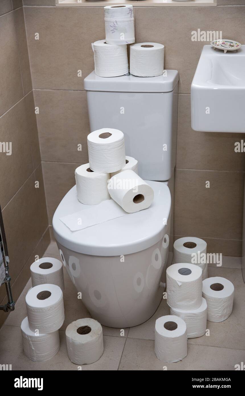 A home interior of a tiled bathroom with white suite and the toilet covered in toilet rolls after panic buying during the Coronavirus Pandemic Stock Photo