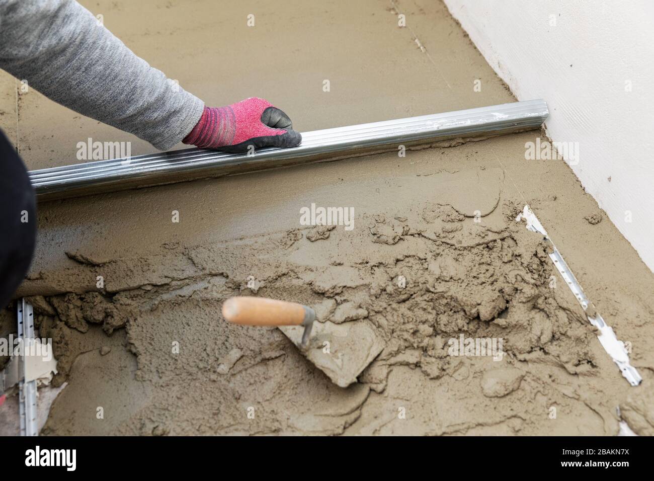 floor construction - man leveling concrete screed Stock Photo