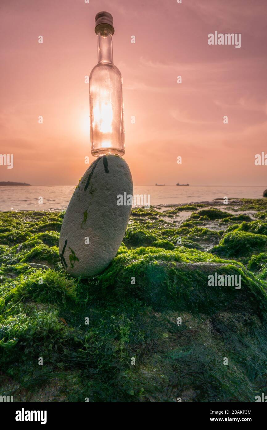 Small bottle placed on a rock with the sun in contrejour. Concept: VITAMIN SEA, bottled Stock Photo