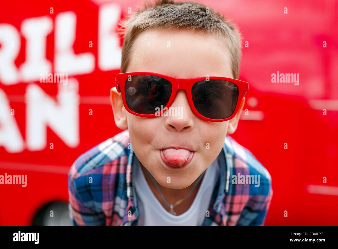 Naughty boy sticks out tongue outdoors in city Stock Photo Alamy