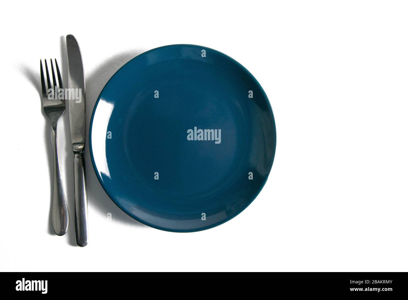 Blue empty plate with fork and knife isolated on white background Stock Photo