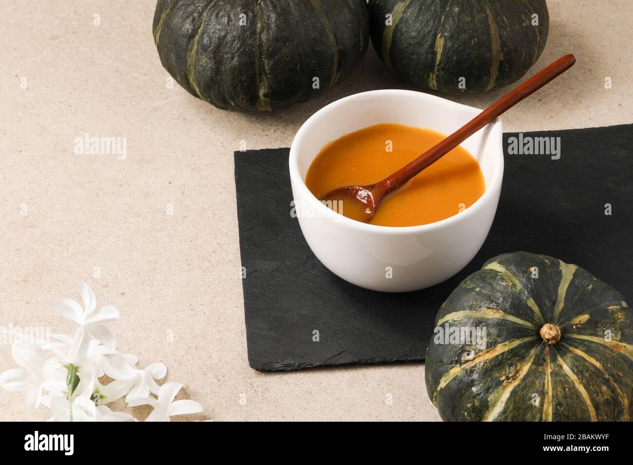 Pumpkin soup in a bowl with wooden spoon and minimalist elegant decorations Stock Photo