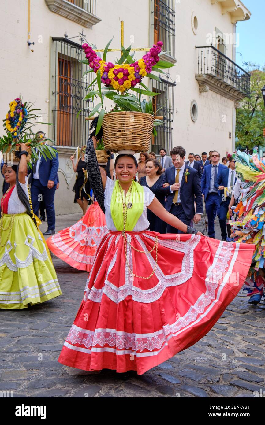 Young female Chinas Oaxaqueñas dancer with red dress and basket of goods on her head during parade in Oaxaca, Mexico Stock Photo