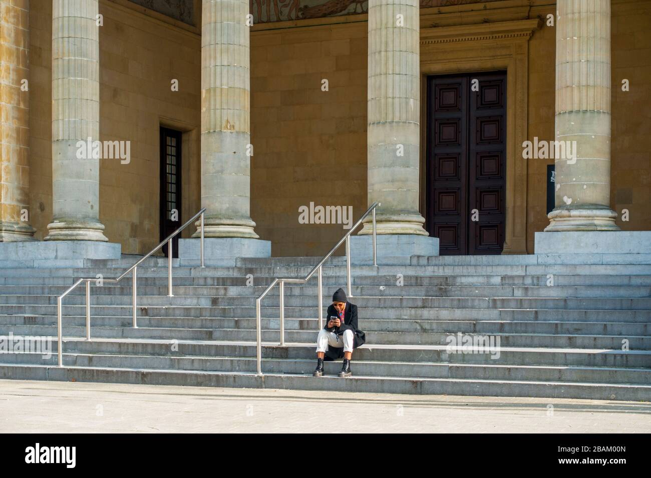 Tourist sitting in front of Museum of Fine Arts / MSK, closed due to 2020 COVID-19 / coronavirus / corona virus pandemic in the city Ghent, Belgium Stock Photo