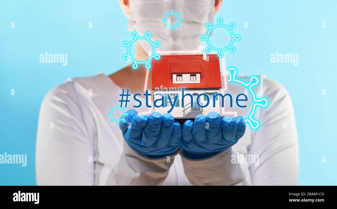Woman in medical gloves and mask holds house in hands. Concept of home stay, quarantine, security inside the house. Covid-19 Corona Prevention Measure Stock Photo