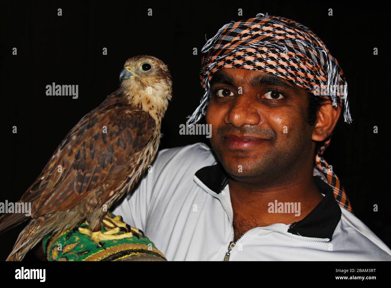 young gentile man with falcon bird at night in Arabia Stock Photo