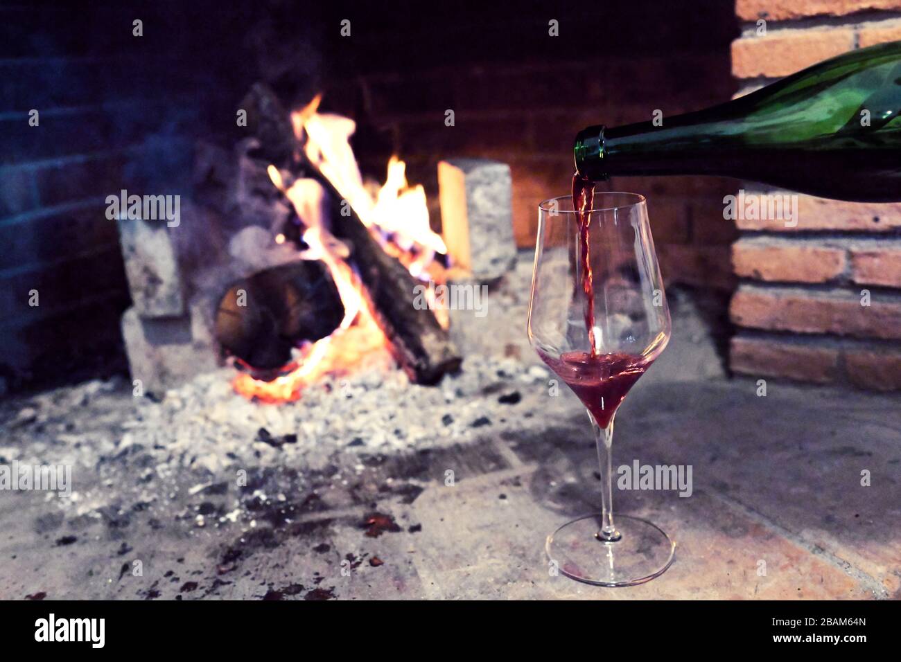 fire burning in the fireplace and in front of a glass of wine Stock