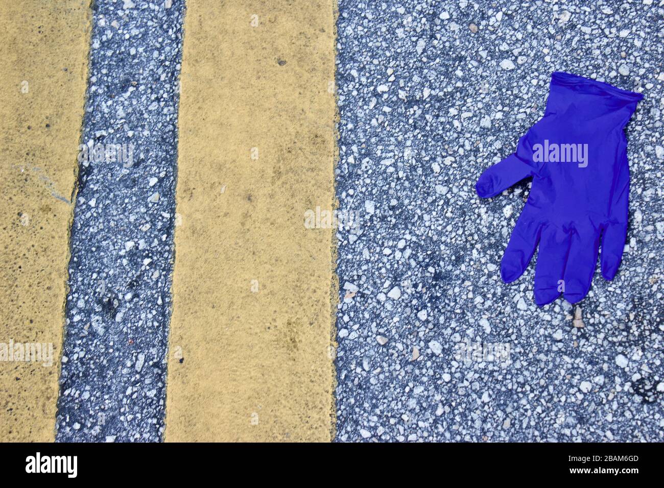Discarded latex gloves in a store parking lot, near storm drain. Byproducts of Corona virus