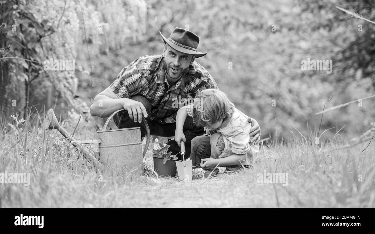 Growing plants. Take care of plants. Boy and father in nature with watering can. Gardening tools. Planting flowers. Dad teaching little son care plants. Little helper in garden. Make planet greener. Stock Photo