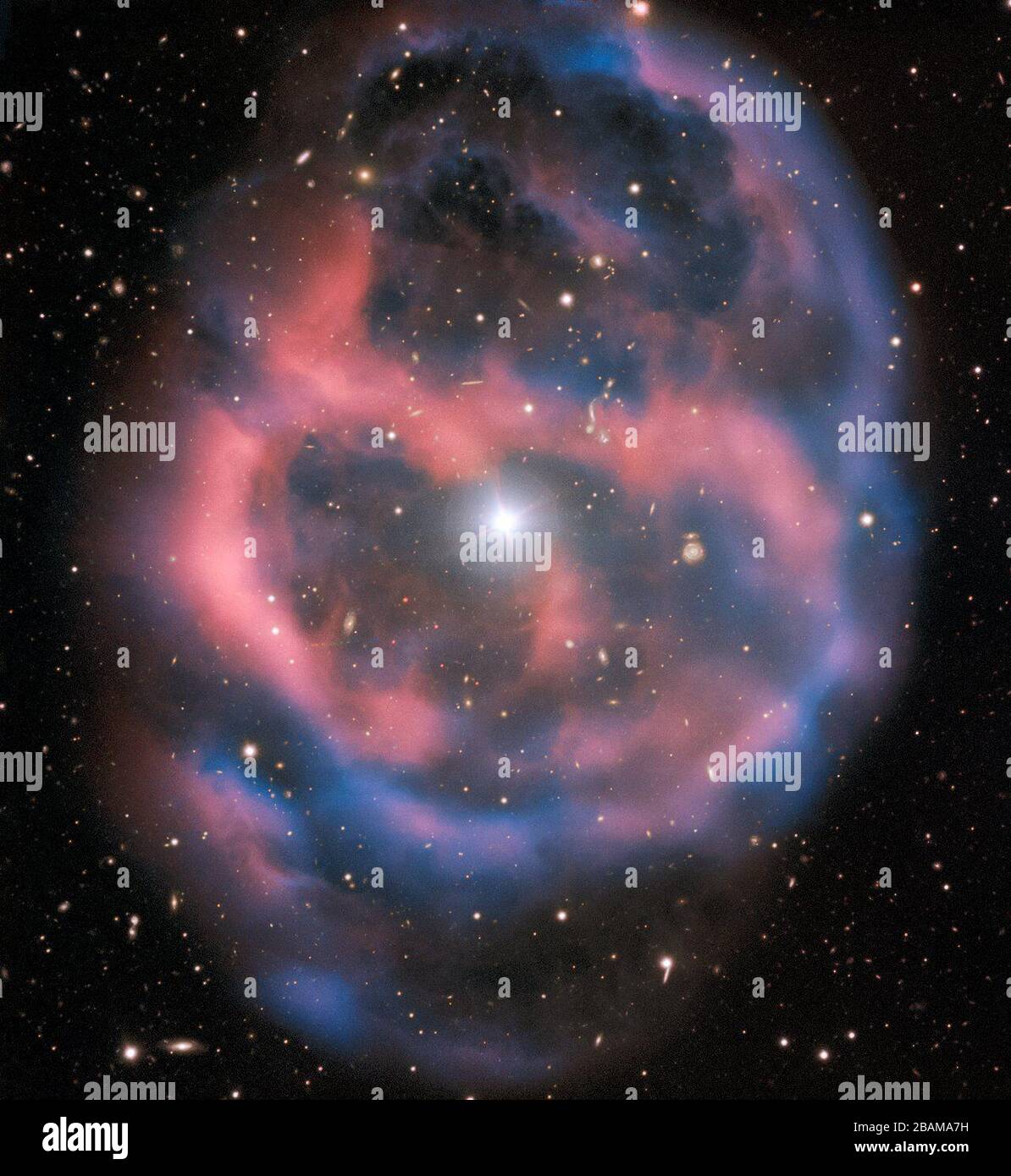 'English: The faint, ephemeral glow emanating from the planetary nebula ESO 577-24 persists for only a short time  — around 10,000 years, a blink of an eye in astronomical terms. ESO’s Very Large Telescope captured this shell of glowing ionised gas — the last breath of the dying star whose simmering remains are visible at the heart of this image. As the gaseous shell of this planetary nebula expands and grows dimmer, it will slowly disappear from sight. This stunning planetary nebula was imaged by one of the VLT’s most versatile instruments, FORS2. The instrument captured the bright, central s Stock Photo