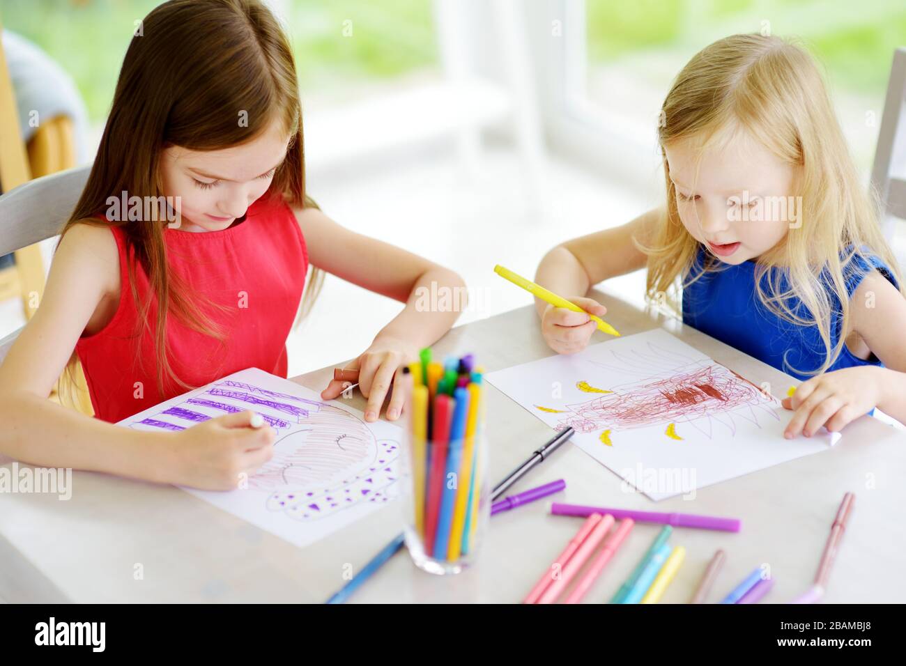 Two young sisters drawing with colorful pencils at home. Creative kids ...