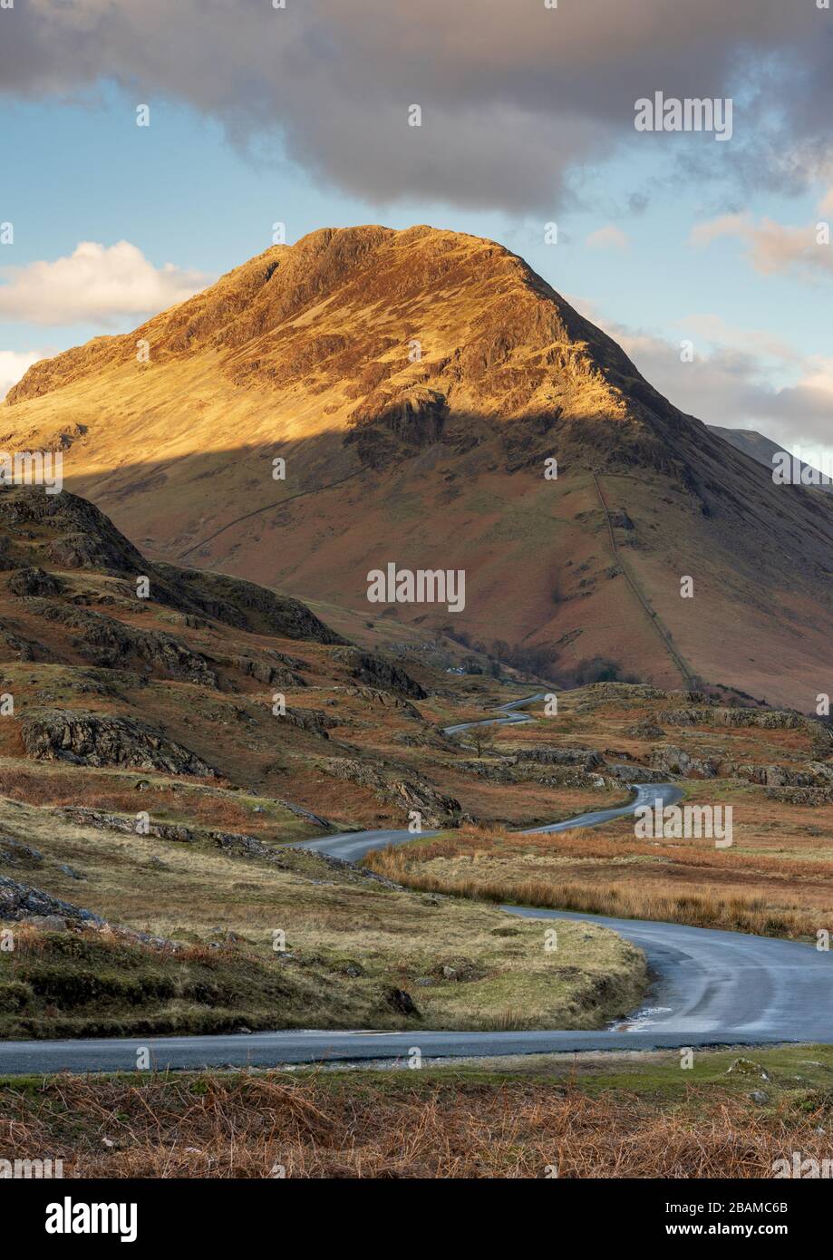 The prominent shape of Yewbarrow, a mountain in the English Lake District, captured in late afternoon as golden light highlights the summit. Stock Photo
