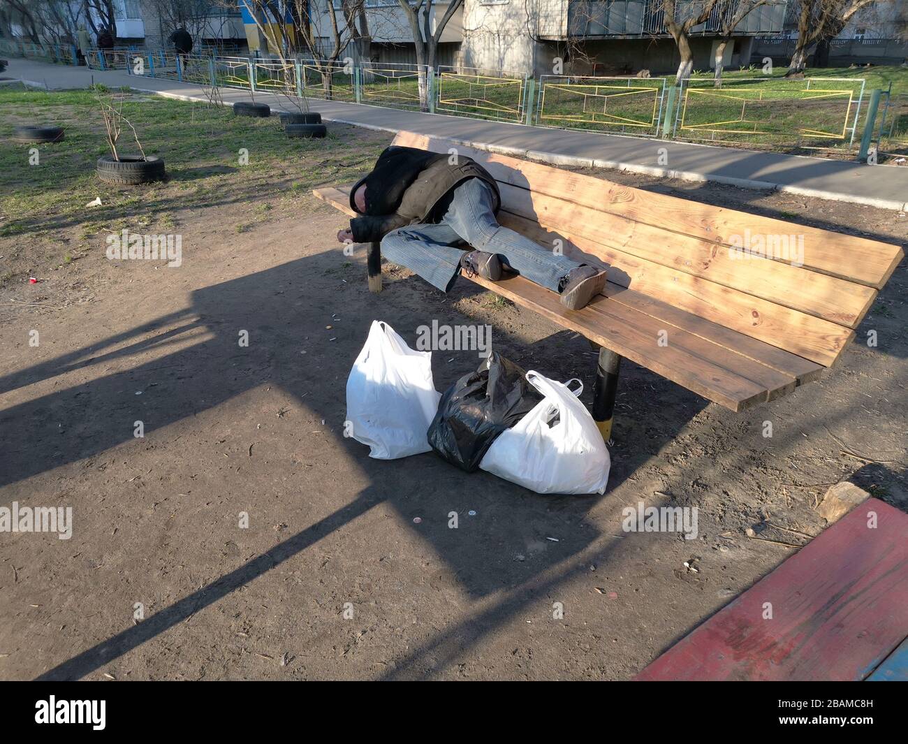 Sleeping homeless man on the wooden bench Stock Photo - Alamy