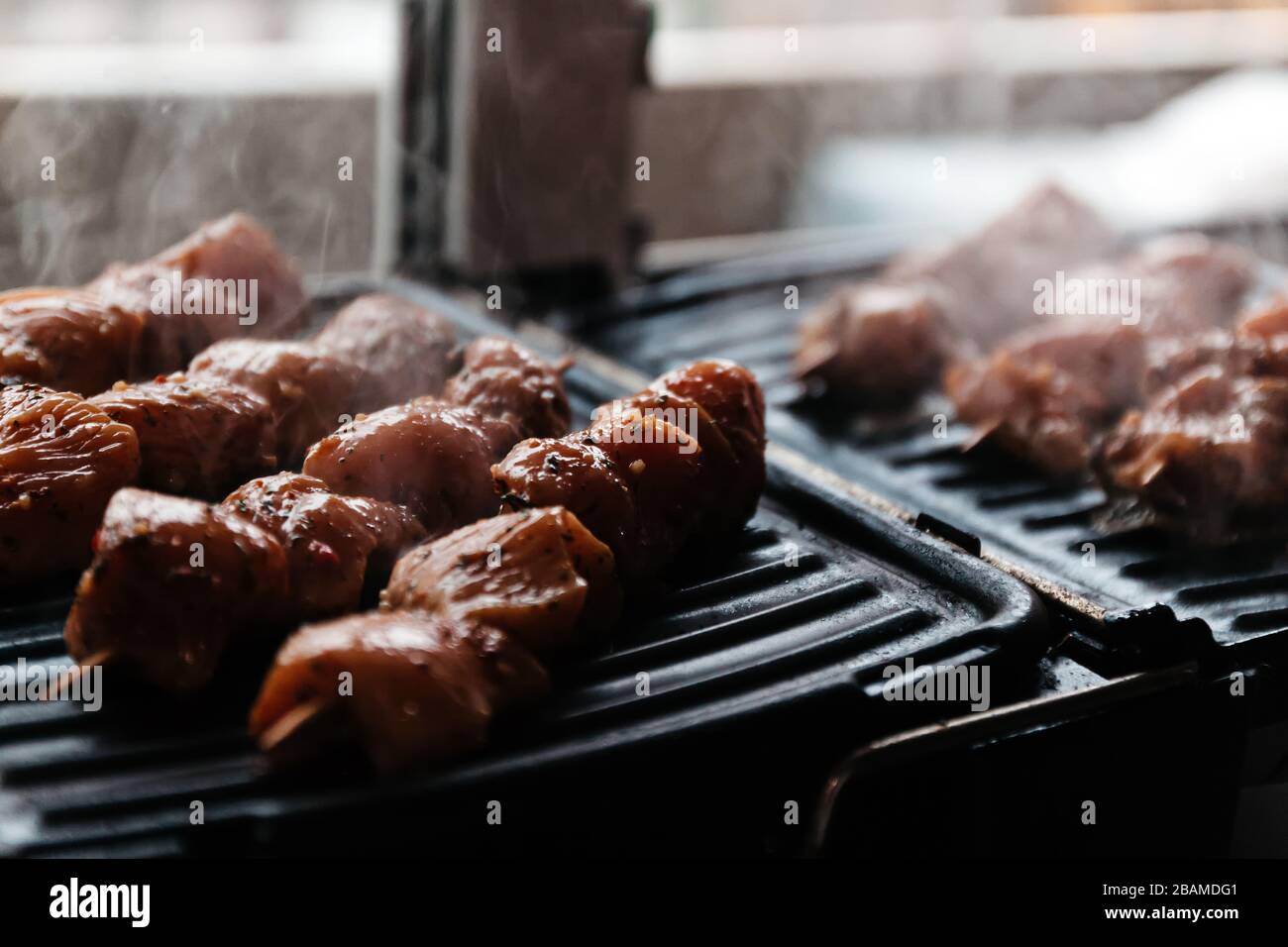 Skewers on skewers from raw meat of pork and beef, chicken cooked on a home electric grill. Top view. Selective focus. Blur Stock Photo
