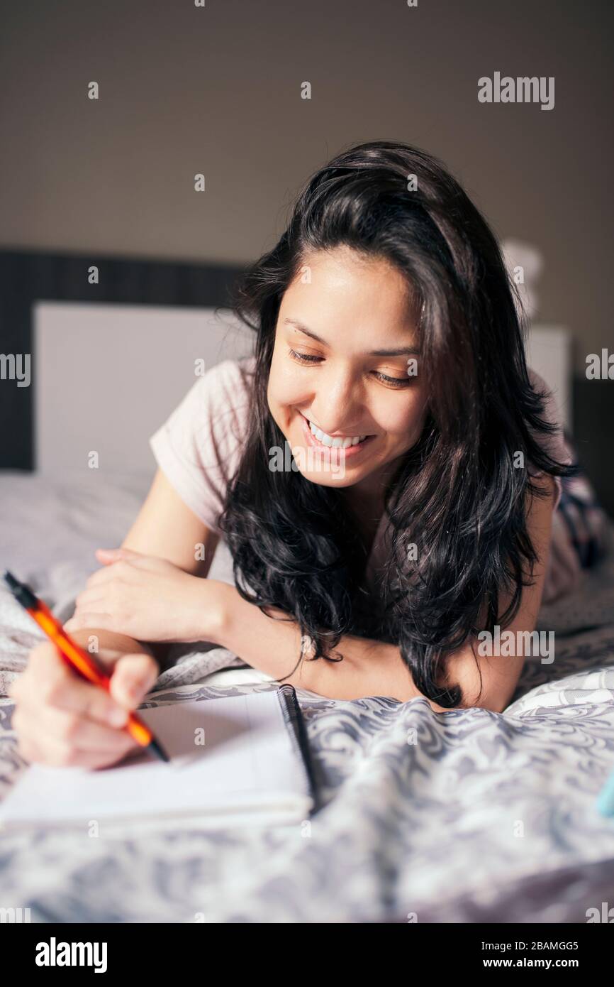 girl taking notes from a class through the tablet in bed Stock Photo