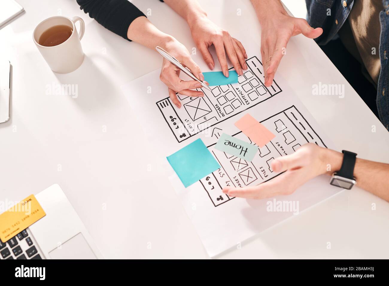 Above view of UI designers discussing new interface design for smartphone and offering different ideas Stock Photo