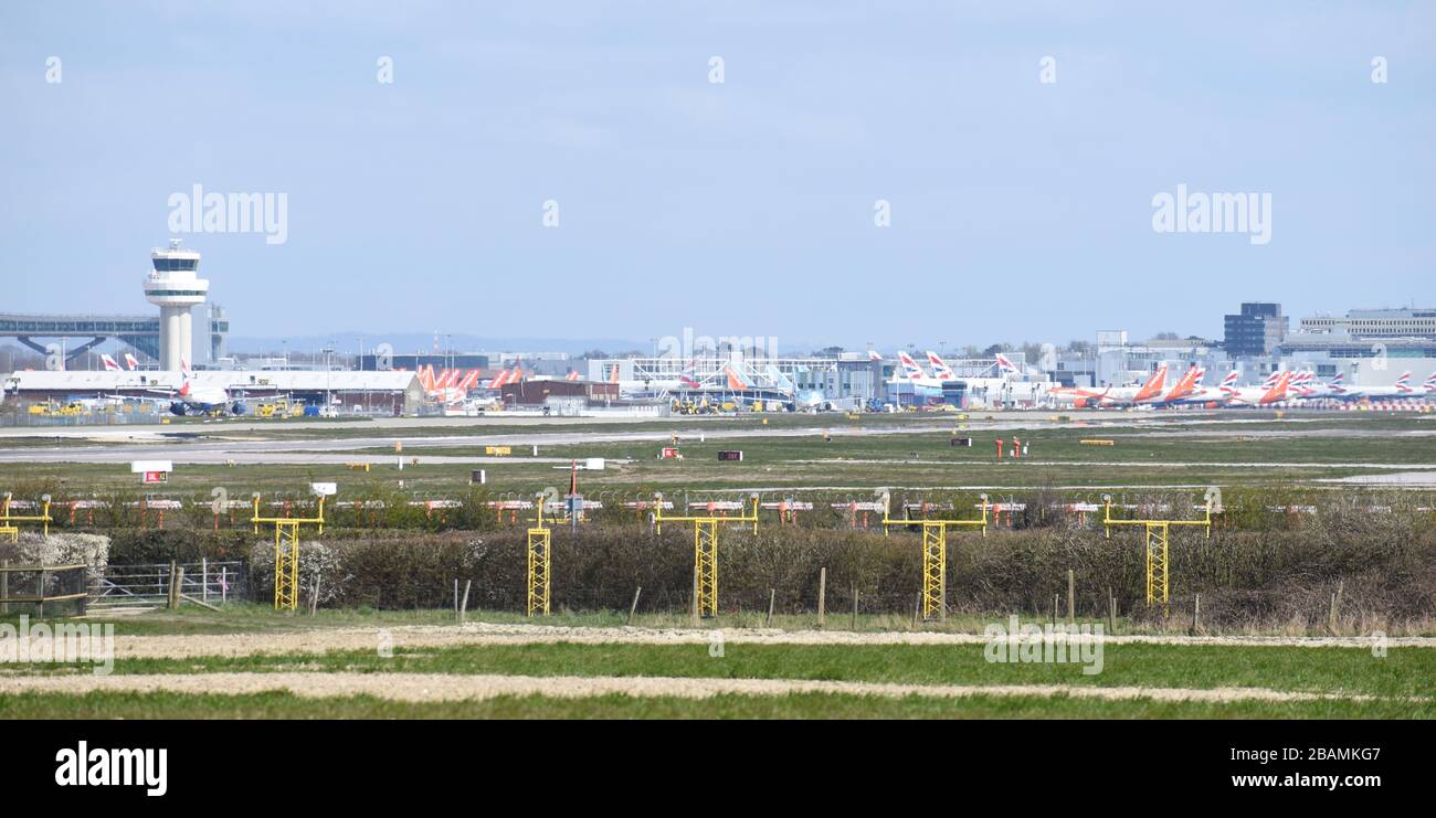 View of the air traffic control tower at Gatwick Airport with lots of British Airways and easyJet grounded planes parked due to a shut down by Covid19 Stock Photo