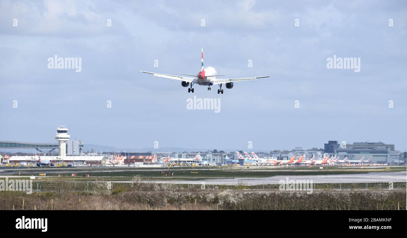 A British Airways Airbus A319-131 callsign G-DBCA comes into land at Gatwick Airport over many grounded aeroplanes due to the Covid-19 coronavirus Stock Photo