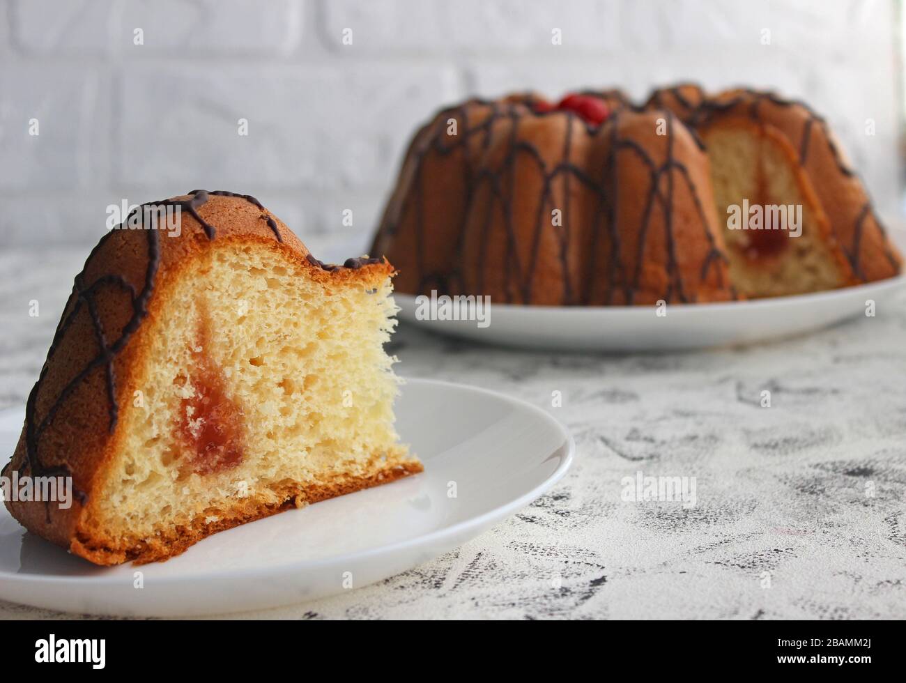 Slices of cake on a plate. In the background is the cake itself. On a dark and light background. Strawberry and Cream Filling with sugar Stock Photo