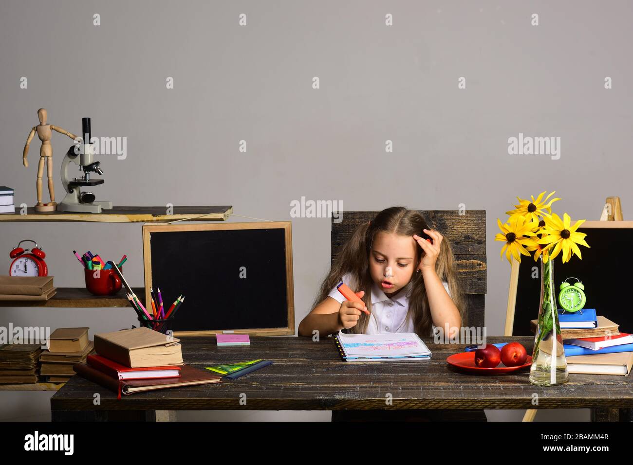 Schoolgirl talks and draws in art book. Girl sits at her desk with ...