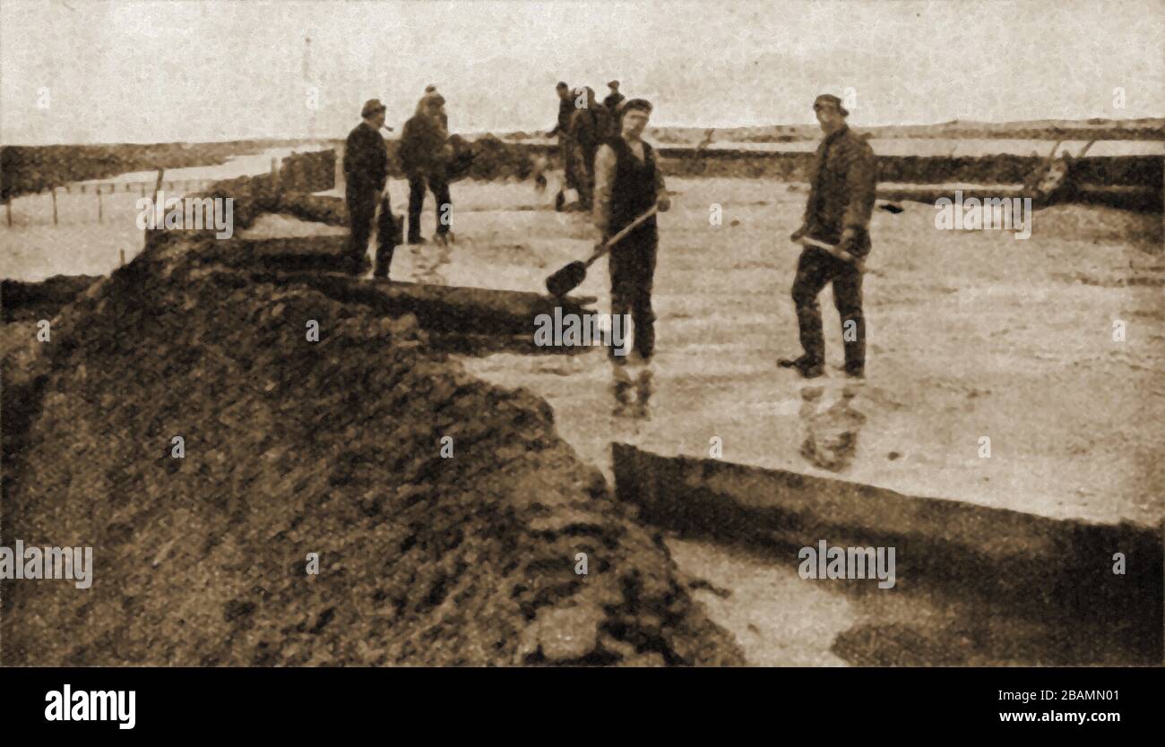 A circa 1930s press photograph of men reclaiming the Zuider Zee (Zuiderzee) . Workmen by  laying  concrete sand and earth over brushwood.  This man-made system of dams and dikes, land reclamation and water drainage work has been carried out since the 1920's. Stock Photo