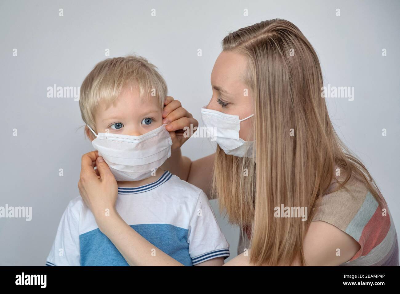Woman with a medical mask puts it on a child Stock Photo