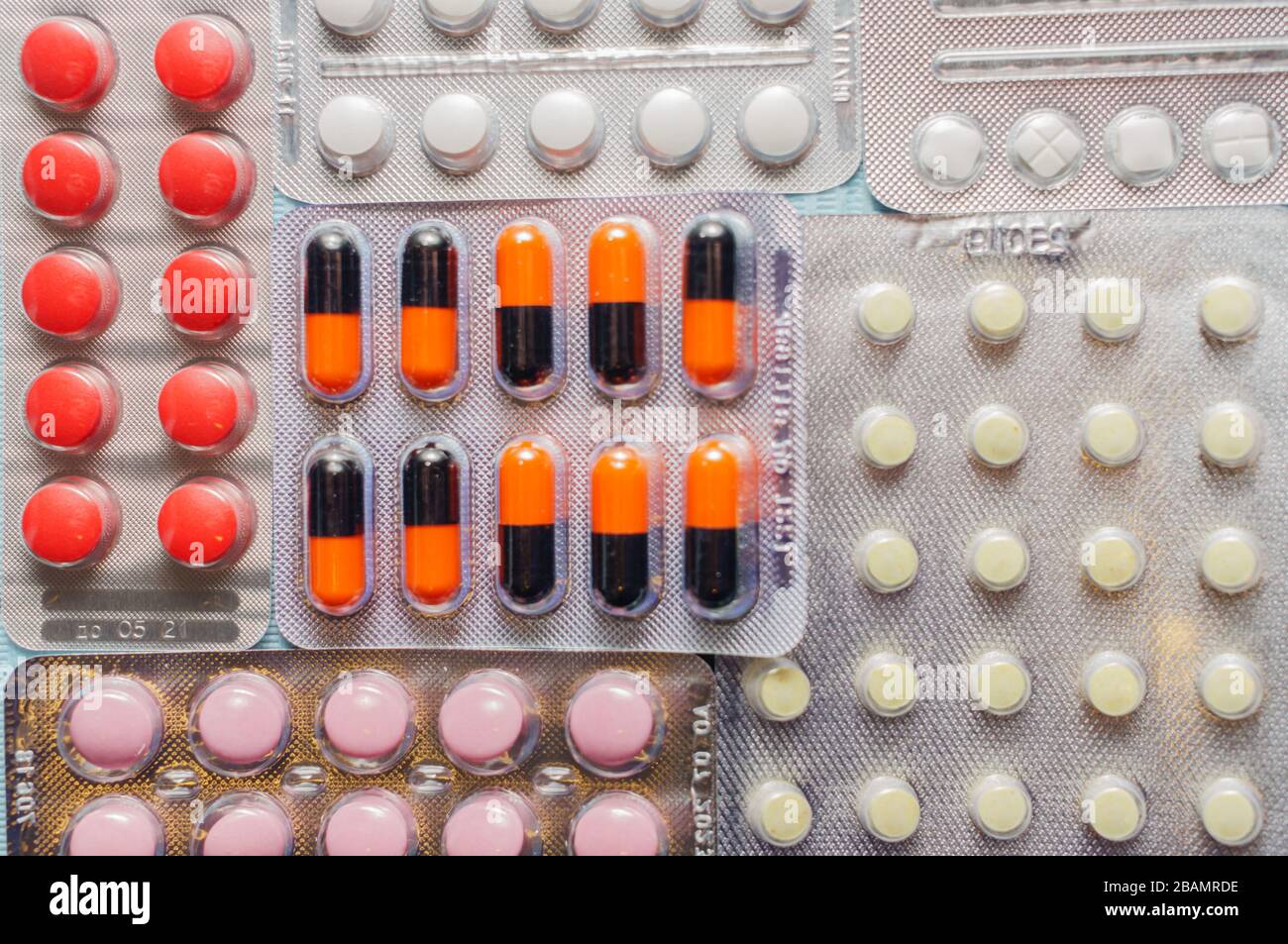 Multicolored tablets and capsules in blisters close-up, top view. The concept of treating human diseases Stock Photo