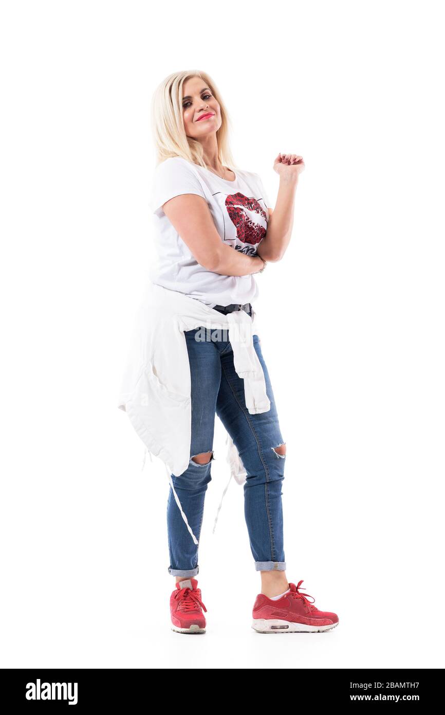 Happy middle age woman in jeans and sneakers with crossed arms smiling