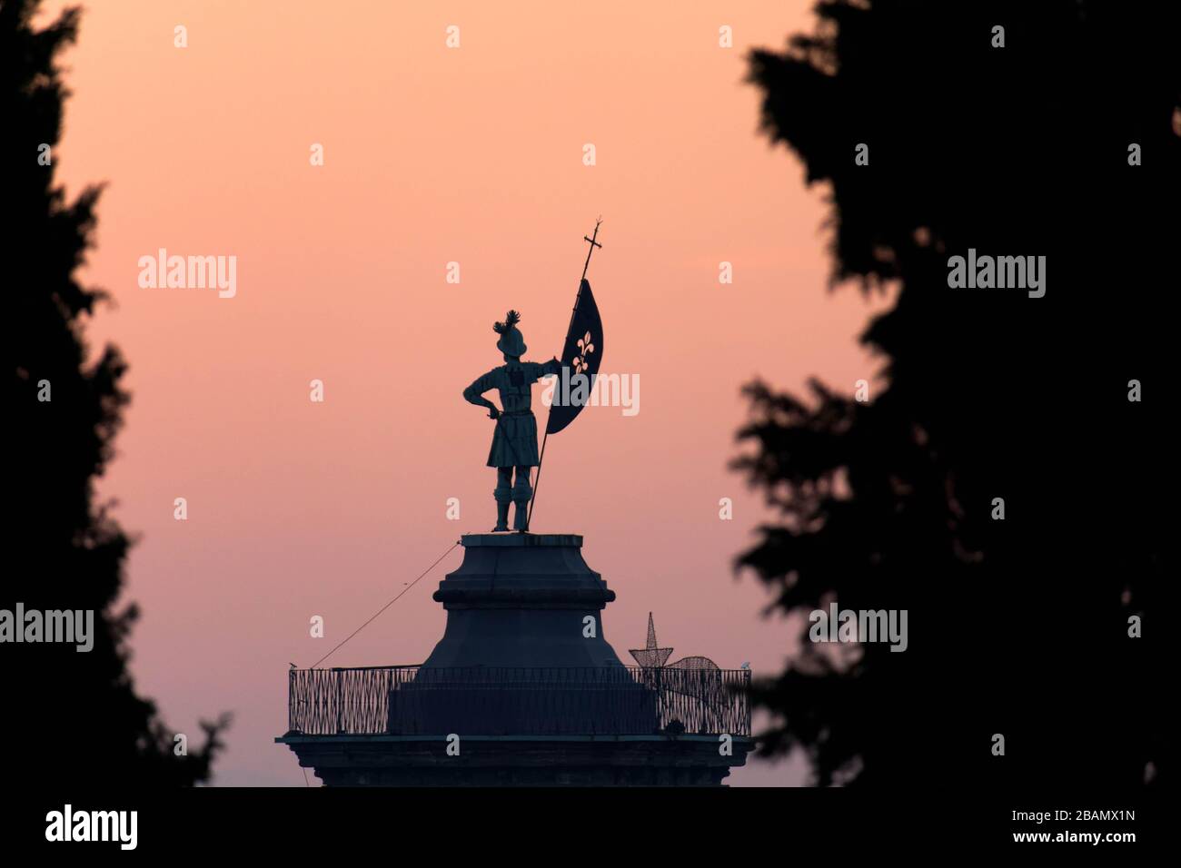 Statue on top of bell tower at Church of Sant'Alessandro della Croce silhouetted against sunrise, Bergamo, Italy Stock Photo