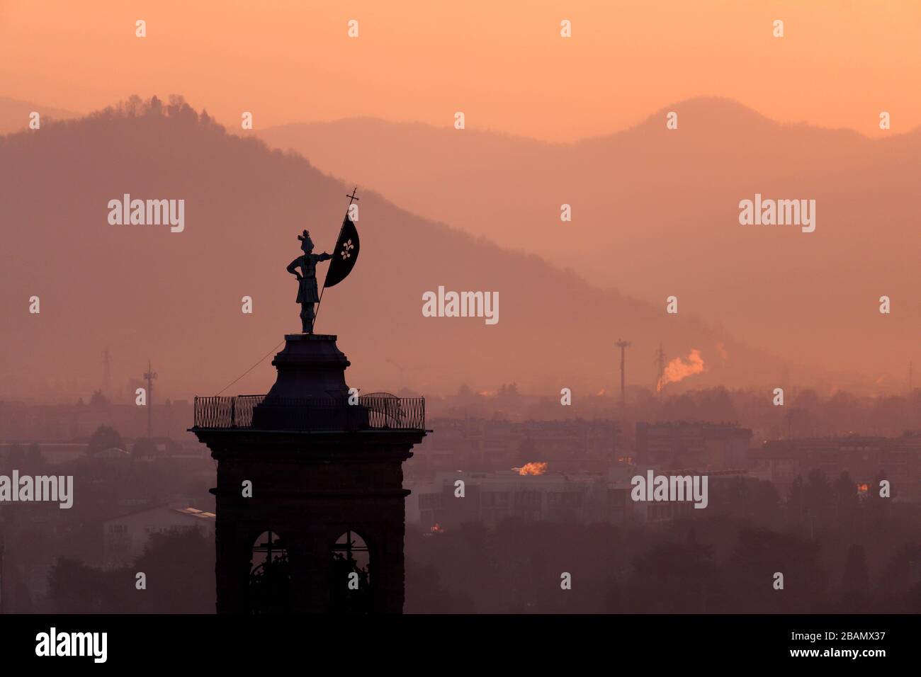 Statue on top of bell tower at Church of Sant'Alessandro della Croce silhouetted against sunrise, Bergamo, Italy Stock Photo