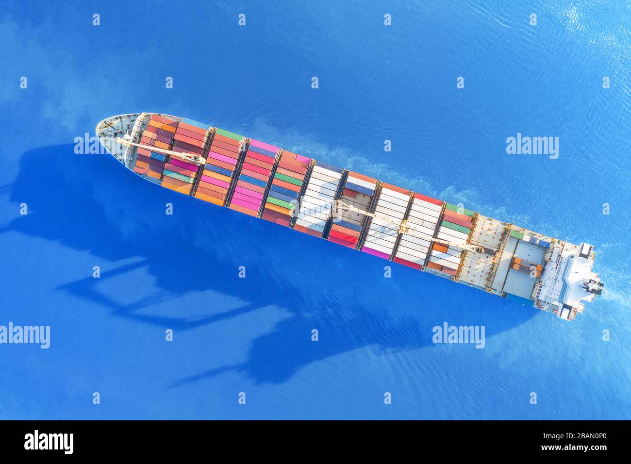Large full loaded container ship sailing bright blue sea. Top aerial view Stock Photo